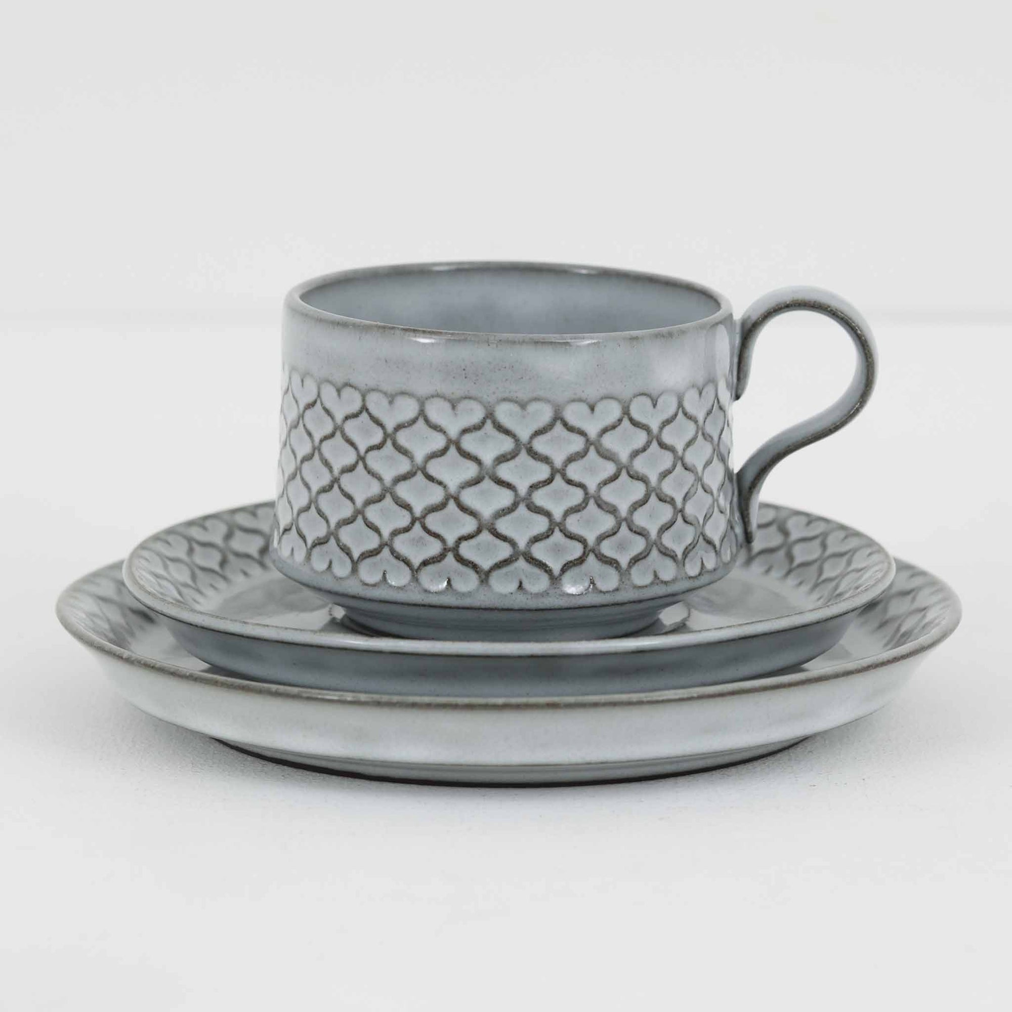 デンマークを代表するデザイナー、イェンス・H・クイストゴーによる「Cordial（コーディアル）」シリーズのヴィンテージ・トリオセット（ティーカップ、ソーサー、プレート）です。1960年代にKronjydenから制作が始まったシリーズは、その後Nissen、Bing&Grondahlと引き継がれ長く愛されたシリーズとなりました。淡いグレーのストーンウェアにハートを連想させる繊細な型押し模様が施されており、デンマークではスウェーデンやフィンランドの陶器メーカーと並んで今でも非常に人気のある商品となります。