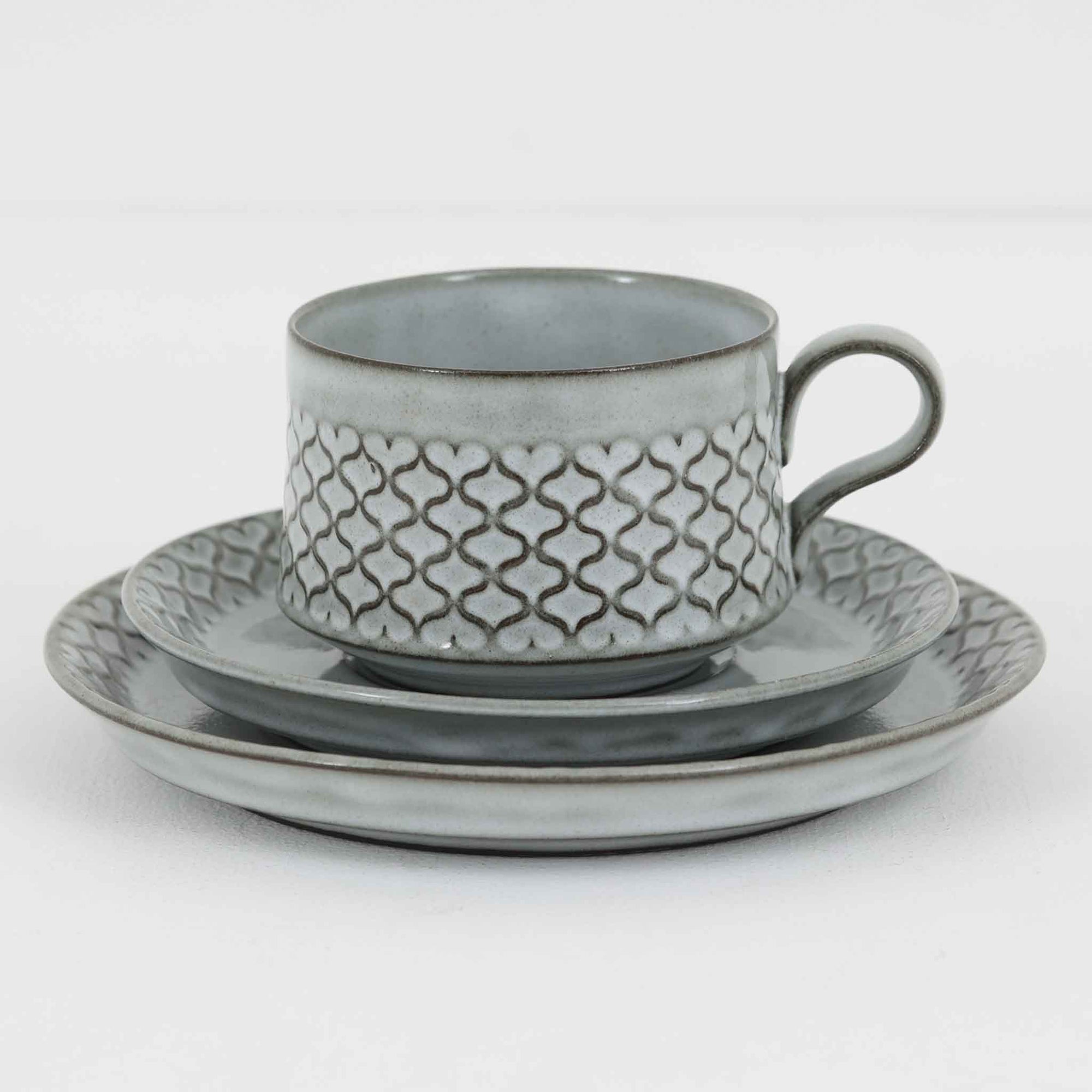 デンマークを代表するデザイナー、イェンス・H・クイストゴーによる「Cordial（コーディアル）」シリーズのヴィンテージ・トリオセット（ティーカップ、ソーサー、プレート）です。1960年代にKronjydenから制作が始まったシリーズは、その後Nissen、Bing&Grondahlと引き継がれ長く愛されたシリーズとなりました。淡いグレーのストーンウェアにハートを連想させる繊細な型押し模様が施されており、デンマークではスウェーデンやフィンランドの陶器メーカーと並んで今でも非常に人気のある商品となります。