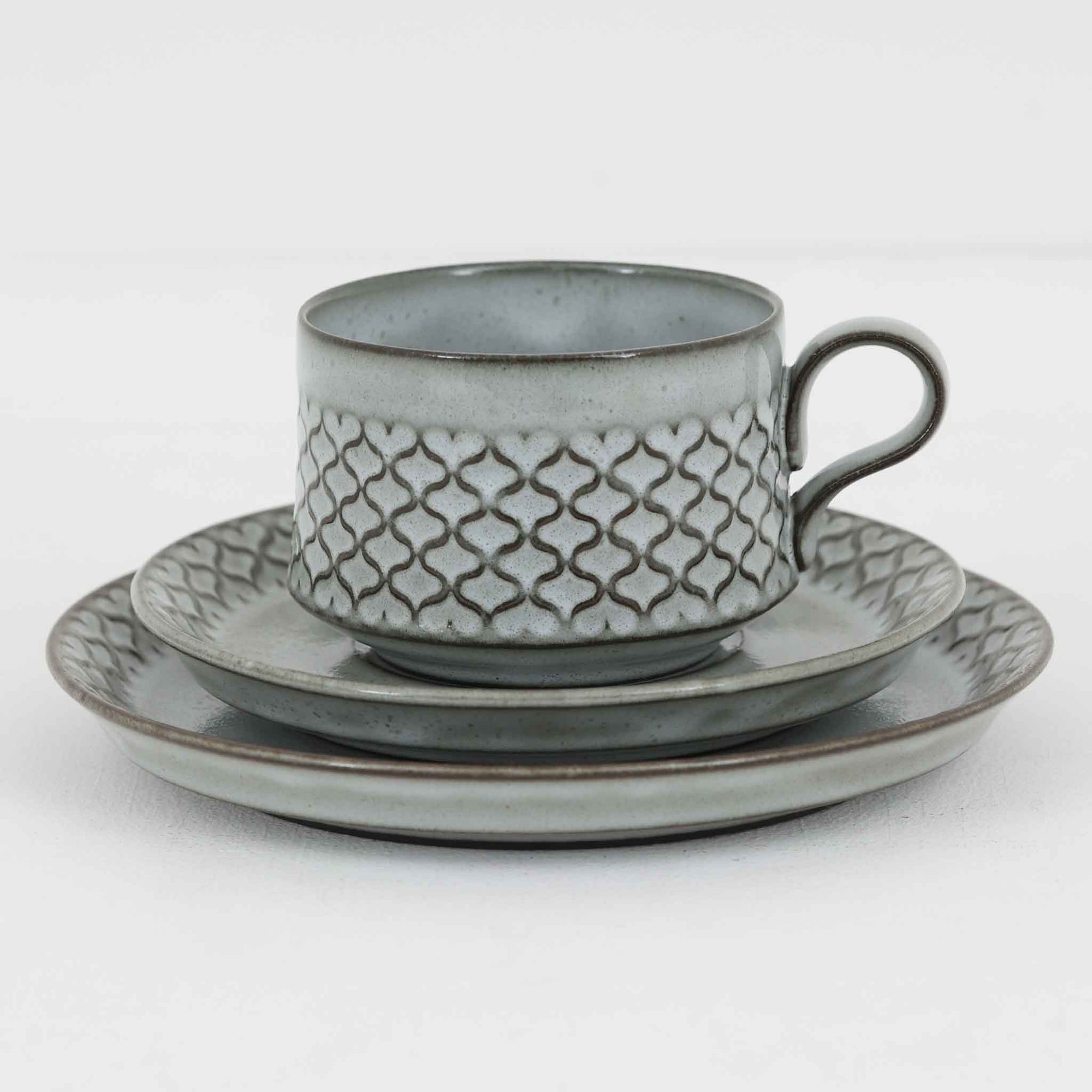 デンマークを代表するデザイナー、イェンス・H・クイストゴーによる「Cordial（コーディアル）」シリーズのヴィンテージ・トリオセット（ティーカップ、ソーサー、プレート）です。1960年代にKronjydenから制作が始まったシリーズは、その後Nissen、Bing&Grondahlと引き継がれ長く愛されたシリーズとなりました。淡いグレーのストーンウェアにハートを連想させる繊細な型押し模様が施されており、デンマークではスウェーデンやフィンランドの陶器メーカーと並んで今でも非常に人気のある商品となります。