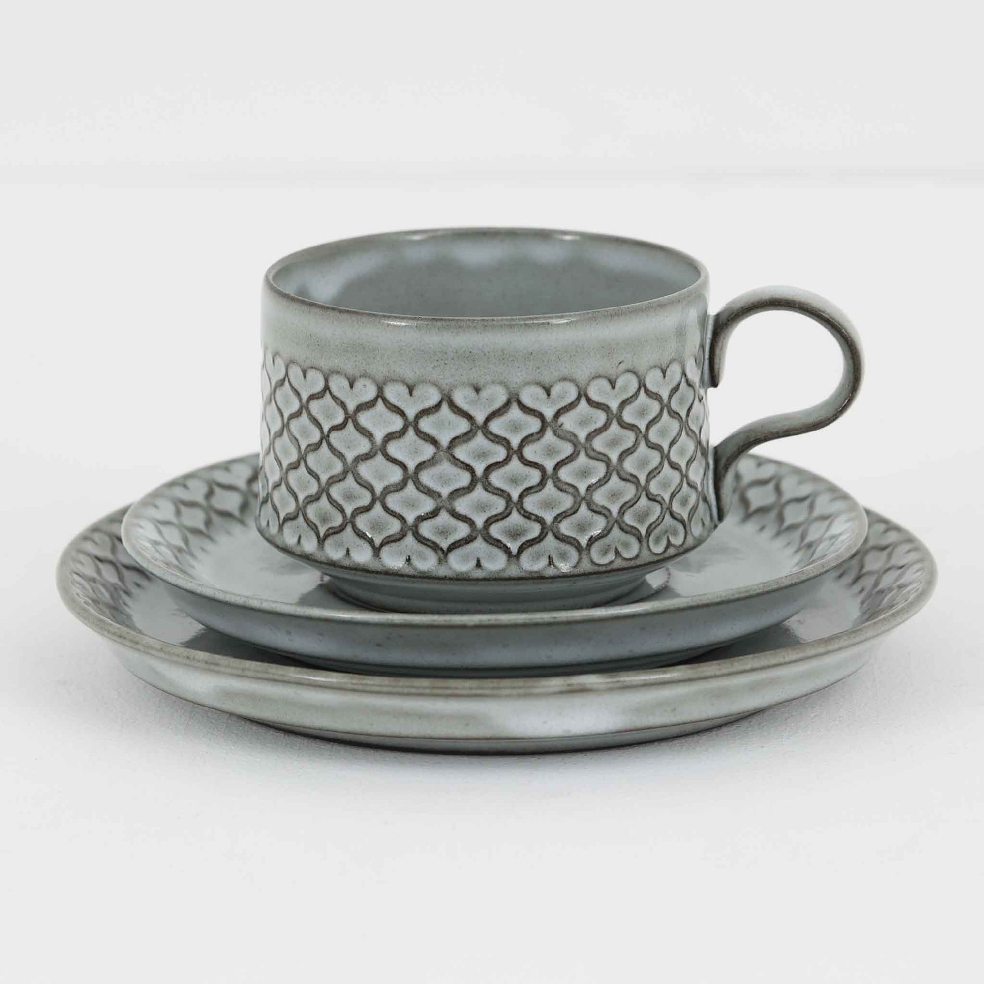 デンマークを代表するデザイナー、イェンス・H・クイストゴーによる「Cordial（コーディアル）」シリーズのヴィンテージ・トリオセット（ティーカップ、ソーサー、プレート）です。1960年代にKronjydenから制作が始まったシリーズは、その後Nissen、Bing&Grondahlと引き継がれ長く愛されたシリーズとなりました。淡いグレーのストーンウェアにハートを連想させる繊細な型押し模様が施されており、デンマークではスウェーデンやフィンランドの陶器メーカーと並んで今でも非常に人気のある商品となります。