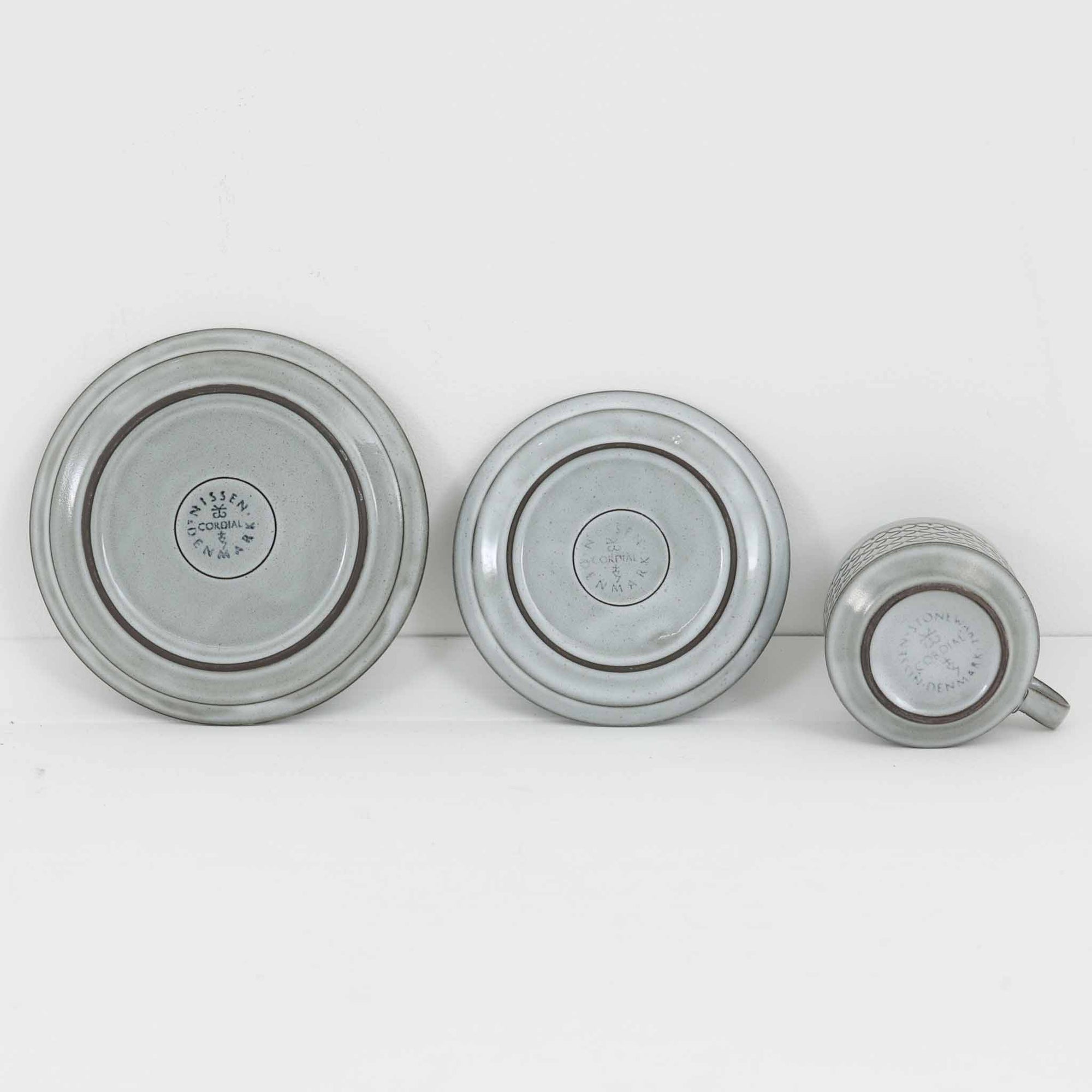 デンマークを代表するデザイナー、イェンス・H・クイストゴーによる「Cordial（コーディアル）」シリーズのヴィンテージ・トリオセット（ティーカップ、ソーサー、プレート）です。1960年代にKronjydenから制作が始まったシリーズは、その後Nissen、Bing&amp;Grondahlと引き継がれ長く愛されたシリーズとなりました。淡いグレーのストーンウェアにハートを連想させる繊細な型押し模様が施されており、デンマークではスウェーデンやフィンランドの陶器メーカーと並んで今でも非常に人気のある商品となります。