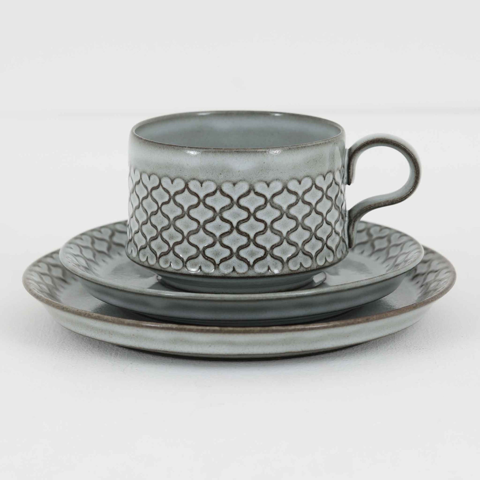 デンマークを代表するデザイナー、イェンス・H・クイストゴーによる「Cordial（コーディアル）」シリーズのヴィンテージ・トリオセット（ティーカップ、ソーサー、プレート）です。1960年代にKronjydenから制作が始まったシリーズは、その後Nissen、Bing&Grondahlと引き継がれ長く愛されたシリーズとなりました。淡いグレーのストーンウェアにハートを連想させる繊細な型押し模様が施されており、デンマークではスウェーデンやフィンランドの陶器メーカーと並んで今でも非常に人気のある商品となります。