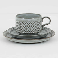 デンマークを代表するデザイナー、イェンス・H・クイストゴーによる「Cordial（コーディアル）」シリーズのヴィンテージ・トリオセット（ティーカップ、ソーサー、プレート）です。1960年代にKronjydenから制作が始まったシリーズは、その後Nissen、Bing&Grondahlと引き継がれ長く愛されたシリーズとなりました。淡いグレーのストーンウェアにハートを連想させる繊細な型押し模様が施されており、デンマークではスウェーデンやフィンランドの陶器メーカーと並んで今でも非常に人気のある商品となります。