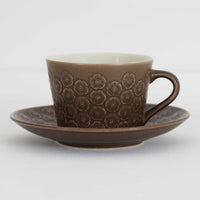 デンマークを代表するデザイナー、イェンス・H・クイストゴーによる「Azur（アズール）」シリーズのヴィンテージカッププ&ソーサーです。1960年代にKronjydenから制作が始まったシリーズは、その後Nissen、Bing&Grondahlと引き継がれ長く愛されたシリーズとなりました。落ち着いたブラウンとプラム色の繊細なフラワーレリーフが施されたストーンウェアは、自然の美しさを食卓にそっと運びます。特にAzurシリーズはヴィンテージ市場でも流通量が極めて少なく高価な逸品となります。