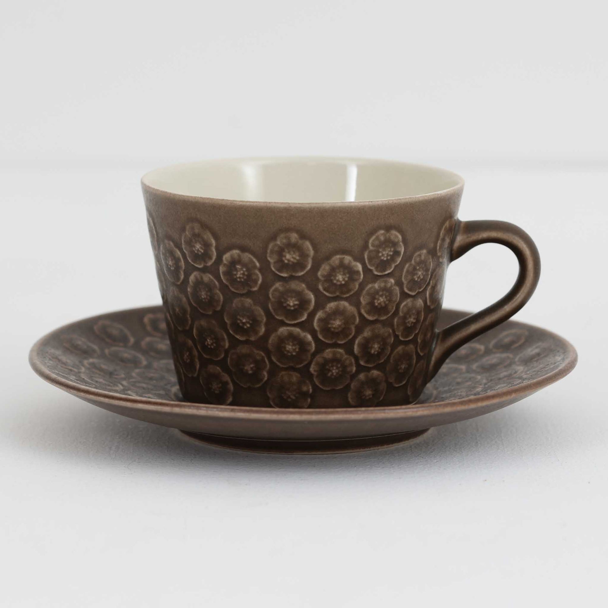 デンマークを代表するデザイナー、イェンス・H・クイストゴーによる「Azur（アズール）」シリーズのヴィンテージカッププ&ソーサーです。1960年代にKronjydenから制作が始まったシリーズは、その後Nissen、Bing&Grondahlと引き継がれ長く愛されたシリーズとなりました。落ち着いたブラウンとプラム色の繊細なフラワーレリーフが施されたストーンウェアは、自然の美しさを食卓にそっと運びます。特にAzurシリーズはヴィンテージ市場でも流通量が極めて少なく高価な逸品となります。