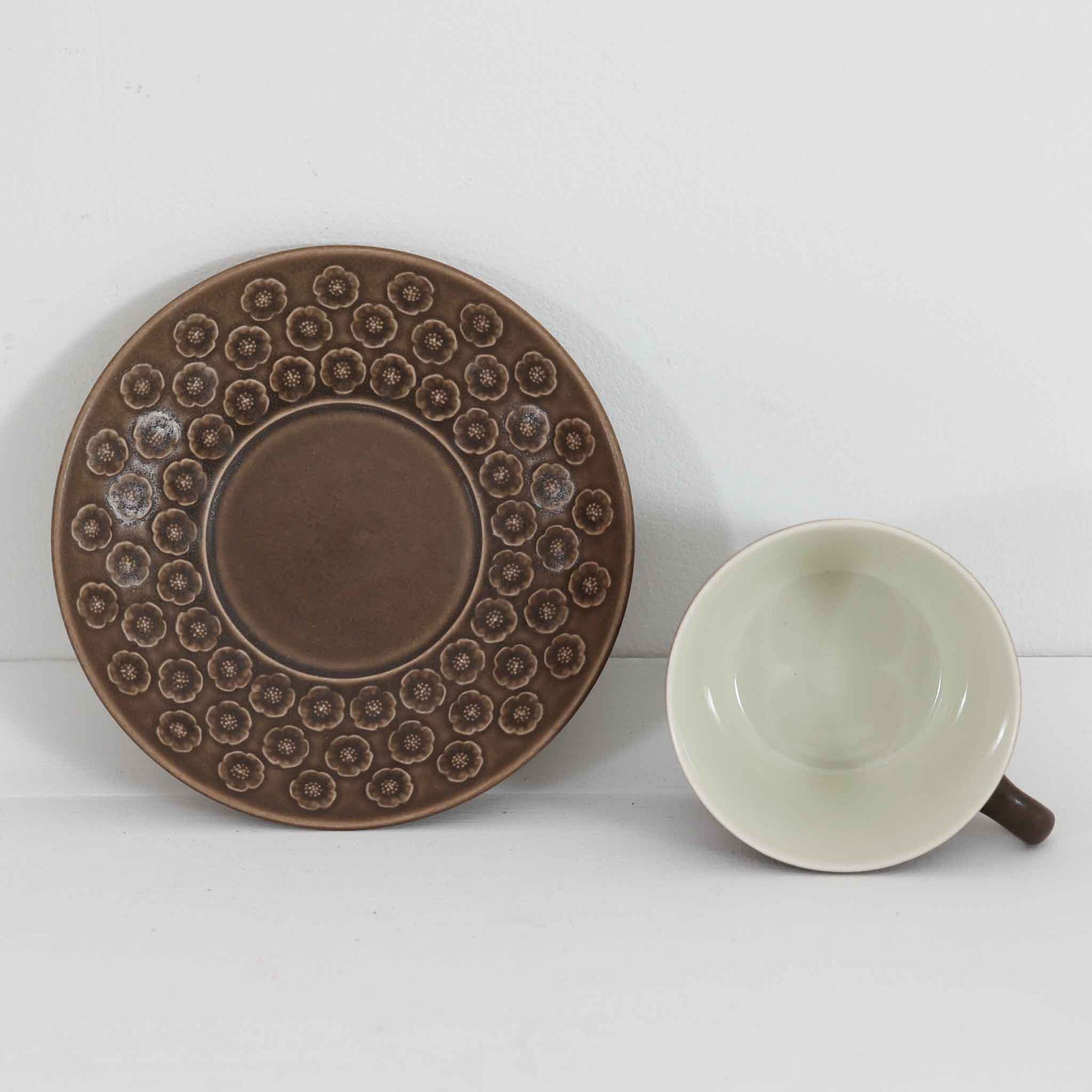 デンマークを代表するデザイナー、イェンス・H・クイストゴーによる「Azur（アズール）」シリーズのヴィンテージカッププ&ソーサーです。1960年代にKronjydenから制作が始まったシリーズは、その後Nissen、Bing&Grondahlと引き継がれ長く愛されたシリーズとなりました。落ち着いたブラウンとプラム色の繊細なフラワーレリーフが施されたストーンウェアは、自然の美しさを食卓にそっと運びます。特にAzurシリーズはヴィンテージ市場でも流通量が極めて少なく高価な逸品となります。