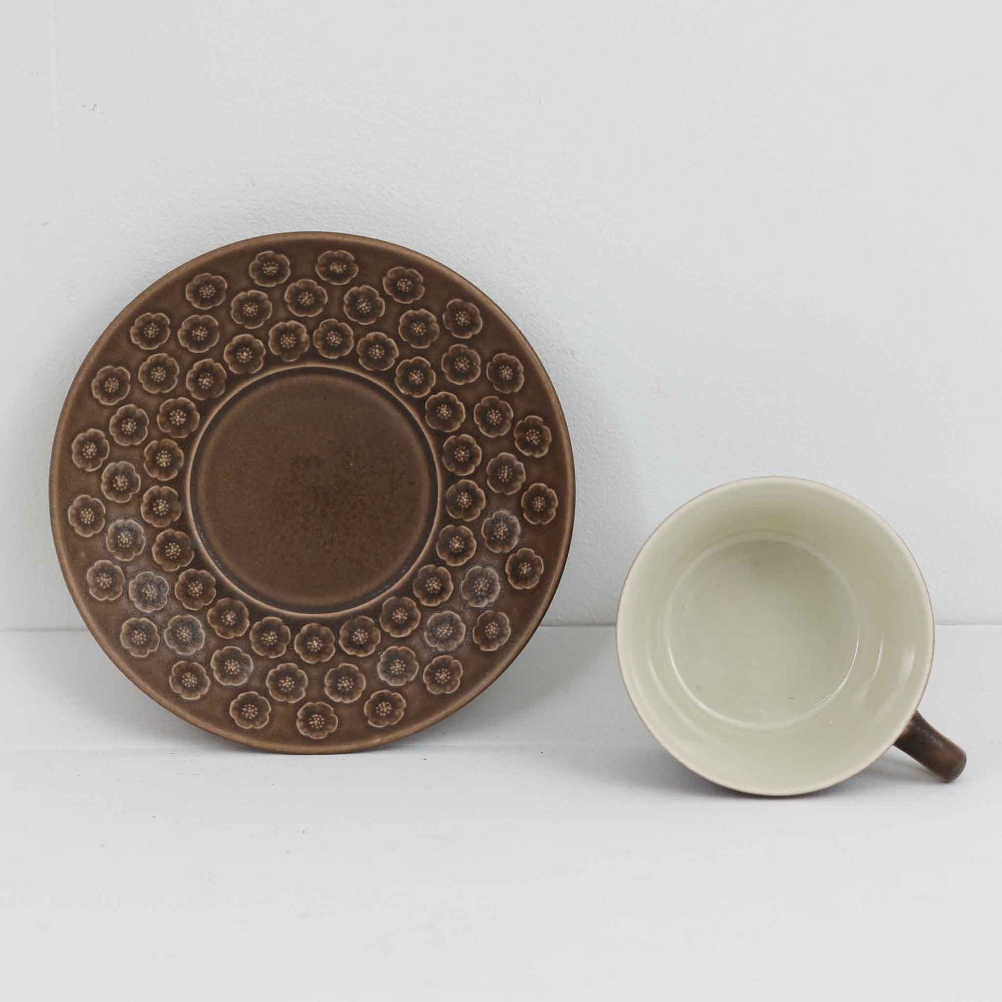 デンマークを代表するデザイナー、イェンス・H・クイストゴーによる「Azur（アズール）」シリーズのヴィンテージカッププ&ソーサーです。1960年代にKronjydenから制作が始まったシリーズは、その後Nissen、Bing&Grondahlと引き継がれ長く愛されたシリーズとなりました。落ち着いたブラウンとプラム色の繊細なフラワーレリーフが施されたストーンウェアは、自然の美しさを食卓にそっと運びます。特にAzurシリーズはヴィンテージ市場でも流通量が極めて少なく高価な逸品となります。