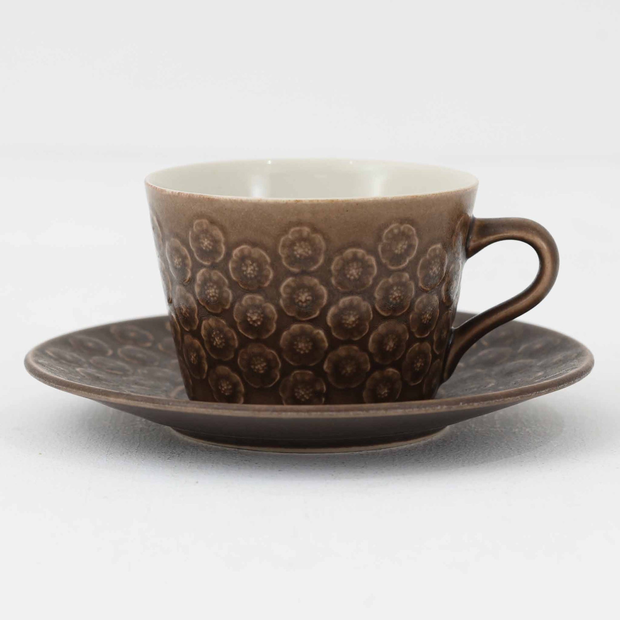 デンマークを代表するデザイナー、イェンス・H・クイストゴーによる「Azur（アズール）」シリーズのヴィンテージカッププ&ソーサーです。1960年代にKronjydenから制作が始まったシリーズは、その後Nissen、Bing&Grondahlと引き継がれ長く愛されたシリーズとなりました。落ち着いたブラウンとプラム色の繊細なフラワーレリーフが施されたストーンウェアは、自然の美しさを食卓にそっと運びます。特にAzurシリーズはヴィンテージ市場でも流通量が極めて少なく高価な逸品となります。