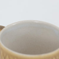 デンマークを代表するデザイナー、イェンス・H・クイストゴーによる「Relief（レリーフ）」シリーズのヴィンテージカップ&ソーサーです。マットなベージュ釉薬に丹念に浮かび上がる葉や木々の〈レリーフ〉装飾が印象的です。素朴で温もりある厚みのあるフォルムは、北欧の静かな森の風景を感じさせます。デンマークではスウェーデンやフィンランドの陶器メーカーと並んで今でも非常に人気のある商品となります。