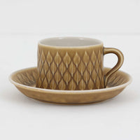 デンマークを代表するデザイナー、イェンス・H・クイストゴーによる「Relief（レリーフ）」シリーズのヴィンテージカップ&ソーサーです。マットなベージュ釉薬に丹念に浮かび上がる葉や木々の〈レリーフ〉装飾が印象的です。素朴で温もりある厚みのあるフォルムは、北欧の静かな森の風景を感じさせます。デンマークではスウェーデンやフィンランドの陶器メーカーと並んで今でも非常に人気のある商品となります。