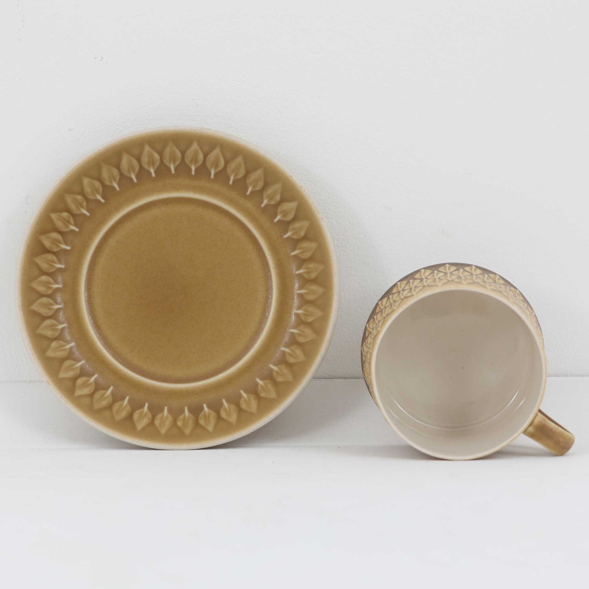 デンマークを代表するデザイナー、イェンス・H・クイストゴーによる「Relief（レリーフ）」シリーズのヴィンテージカップ&amp;ソーサーです。マットなベージュ釉薬に丹念に浮かび上がる葉や木々の〈レリーフ〉装飾が印象的です。素朴で温もりある厚みのあるフォルムは、北欧の静かな森の風景を感じさせます。デンマークではスウェーデンやフィンランドの陶器メーカーと並んで今でも非常に人気のある商品となります。