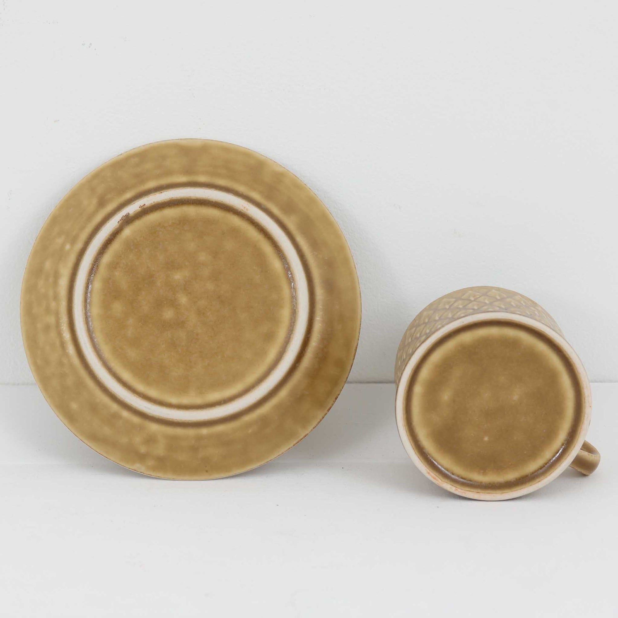 デンマークを代表するデザイナー、イェンス・H・クイストゴーによる「Relief（レリーフ）」シリーズのヴィンテージカップ&amp;ソーサーです。マットなベージュ釉薬に丹念に浮かび上がる葉や木々の〈レリーフ〉装飾が印象的です。素朴で温もりある厚みのあるフォルムは、北欧の静かな森の風景を感じさせます。デンマークではスウェーデンやフィンランドの陶器メーカーと並んで今でも非常に人気のある商品となります。