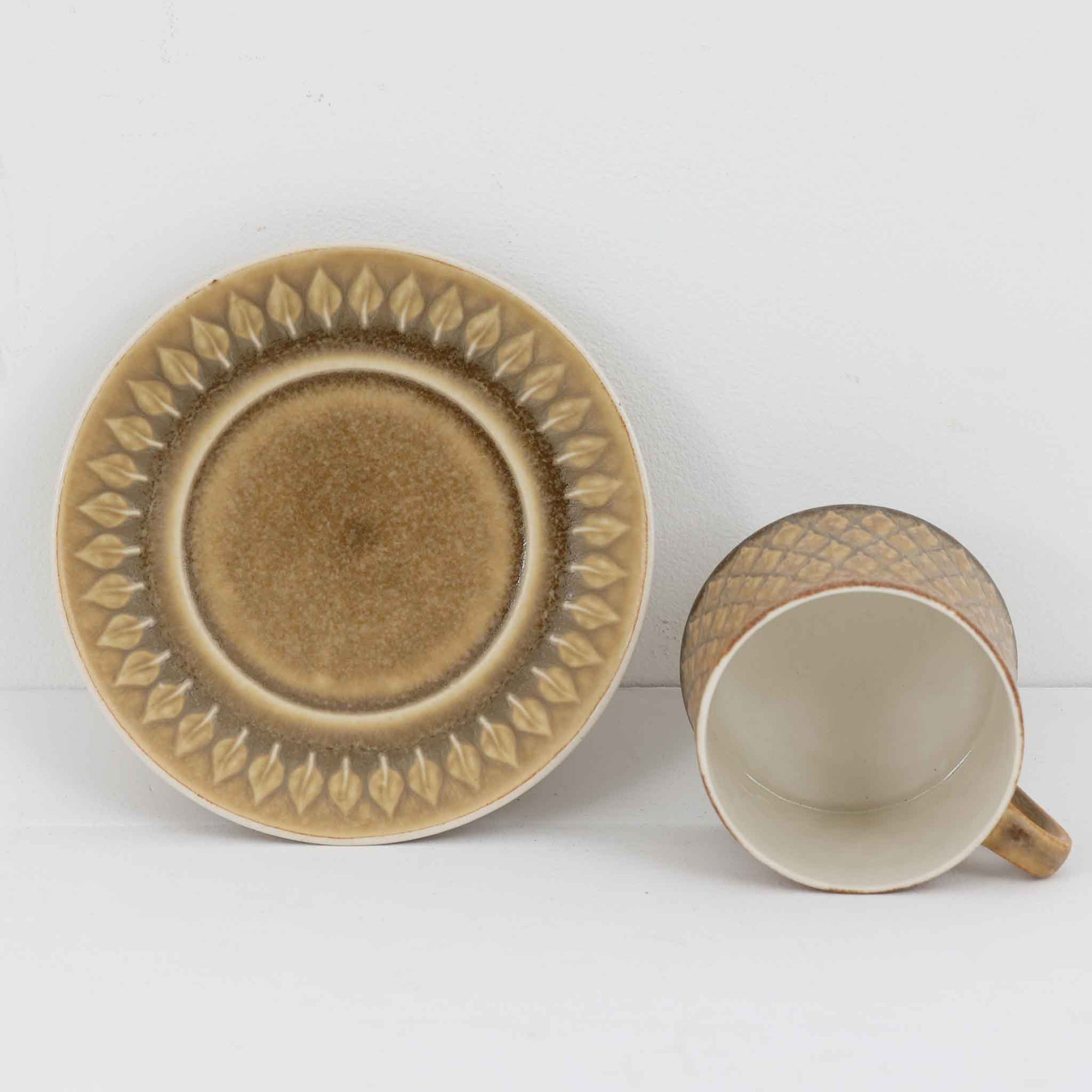 デンマークを代表するデザイナー、イェンス・H・クイストゴーによる「Relief（レリーフ）」シリーズのヴィンテージカップ&ソーサーです。マットなベージュ釉薬に丹念に浮かび上がる葉や木々の〈レリーフ〉装飾が印象的です。素朴で温もりある厚みのあるフォルムは、北欧の静かな森の風景を感じさせます。デンマークではスウェーデンやフィンランドの陶器メーカーと並んで今でも非常に人気のある商品となります。