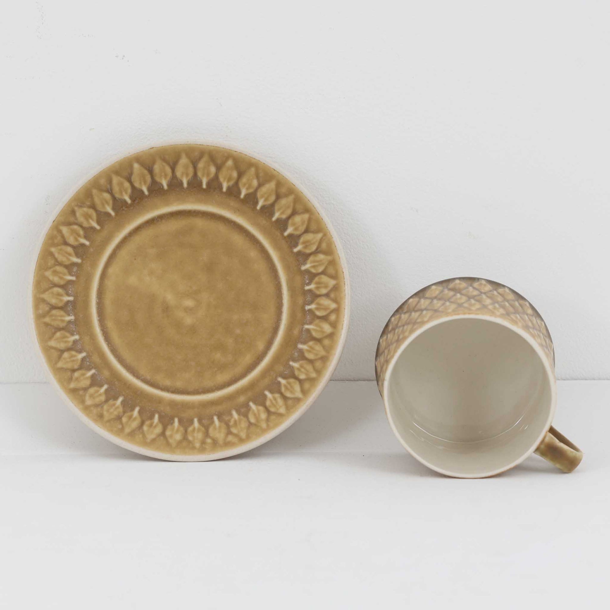 デンマークを代表するデザイナー、イェンス・H・クイストゴーによる「Relief（レリーフ）」シリーズのヴィンテージカップ&amp;ソーサーです。マットなベージュ釉薬に丹念に浮かび上がる葉や木々の〈レリーフ〉装飾が印象的です。素朴で温もりある厚みのあるフォルムは、北欧の静かな森の風景を感じさせます。デンマークではスウェーデンやフィンランドの陶器メーカーと並んで今でも非常に人気のある商品となります。