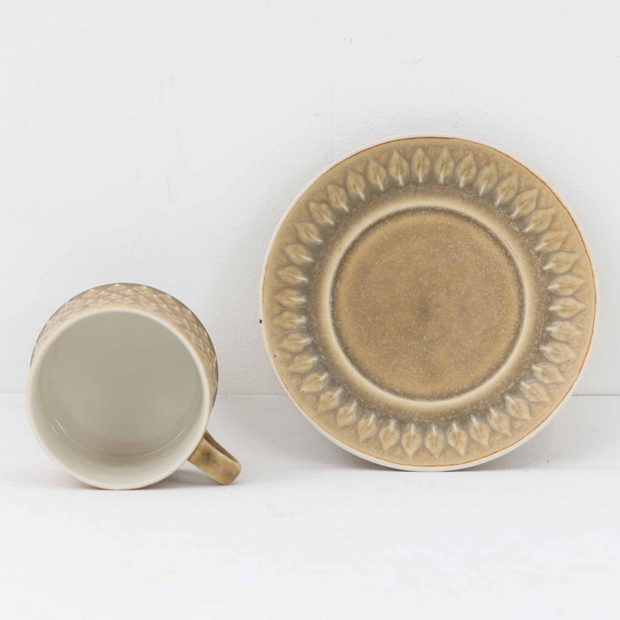 デンマークを代表するデザイナー、イェンス・H・クイストゴーによる「Relief（レリーフ）」シリーズのヴィンテージカップ&ソーサーです。マットなベージュ釉薬に丹念に浮かび上がる葉や木々の〈レリーフ〉装飾が印象的です。素朴で温もりある厚みのあるフォルムは、北欧の静かな森の風景を感じさせます。デンマークではスウェーデンやフィンランドの陶器メーカーと並んで今でも非常に人気のある商品となります。