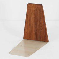 北欧デザインの温もりを感じさせる、デンマーク製ヴィンテージのブックエンドです。1960〜80年代頃に製造されたとみられ、素材には希少なチーク材を使用。深みのある色合いと美しい木目は、経年によってさらに味わいを増し、空間に落ち着きと上質さをもたらします。シンプルでありながら洗練されたフォルムは、北欧モダンらしいミニマルな美しさを体現しており、実用性とインテリア性を兼ね備え、書棚やデスクまわりを上品に演出します。