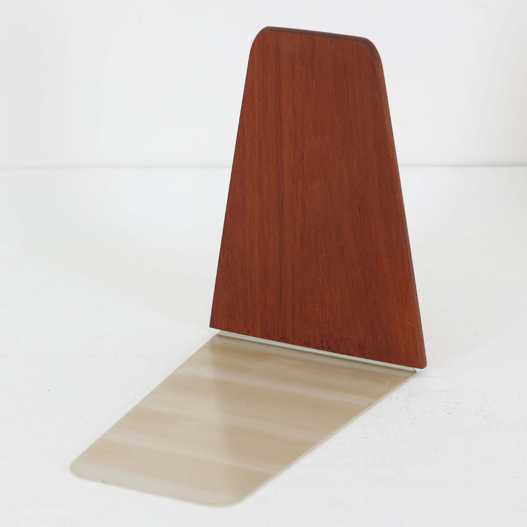 北欧デザインの温もりを感じさせる、デンマーク製ヴィンテージのブックエンドです。1960〜80年代頃に製造されたとみられ、素材には希少なチーク材を使用。深みのある色合いと美しい木目は、経年によってさらに味わいを増し、空間に落ち着きと上質さをもたらします。シンプルでありながら洗練されたフォルムは、北欧モダンらしいミニマルな美しさを体現しており、実用性とインテリア性を兼ね備え、書棚やデスクまわりを上品に演出します。