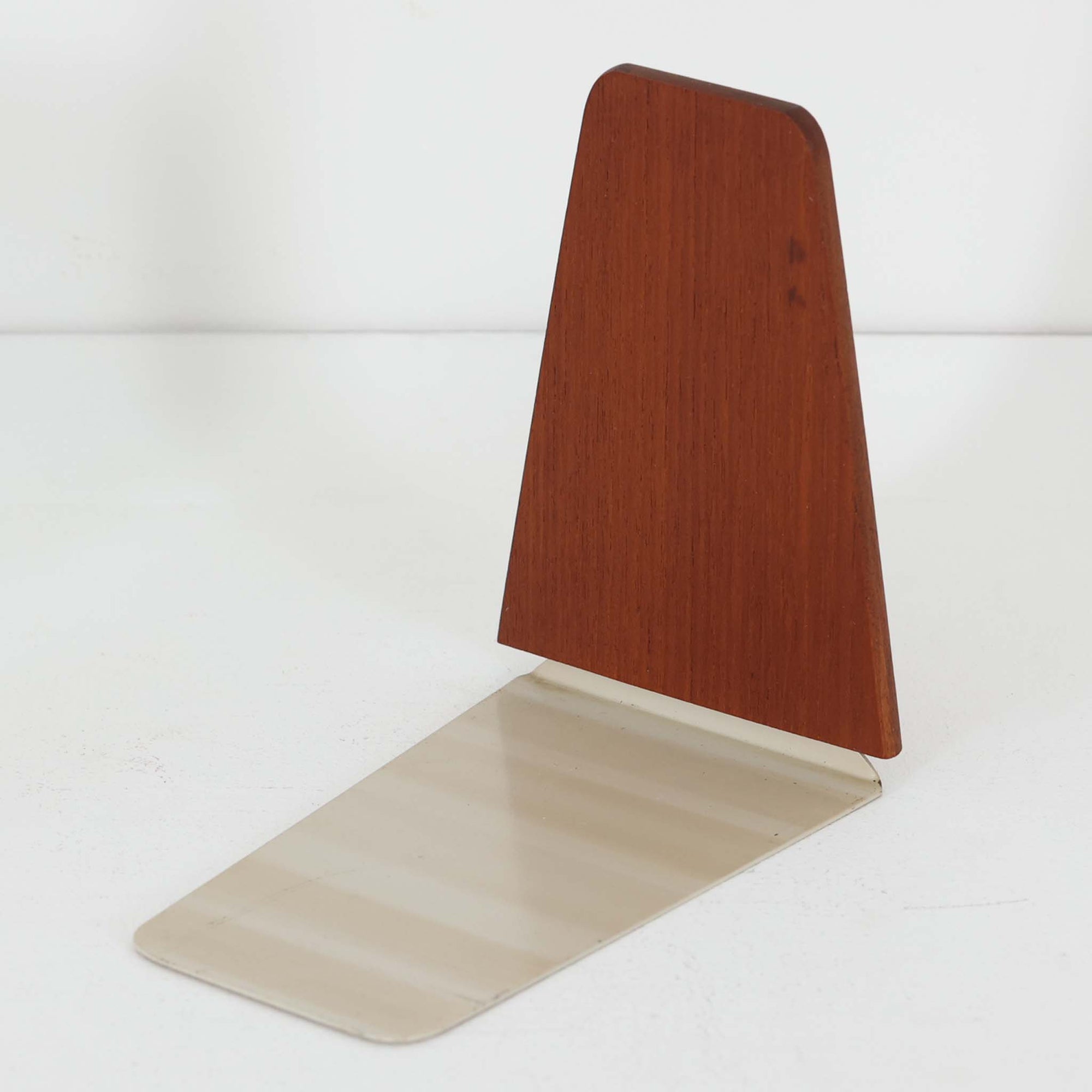 北欧デザインの温もりを感じさせる、デンマーク製ヴィンテージのブックエンドです。1960〜80年代頃に製造されたとみられ、素材には希少なチーク材を使用。深みのある色合いと美しい木目は、経年によってさらに味わいを増し、空間に落ち着きと上質さをもたらします。シンプルでありながら洗練されたフォルムは、北欧モダンらしいミニマルな美しさを体現しており、実用性とインテリア性を兼ね備え、書棚やデスクまわりを上品に演出します。
