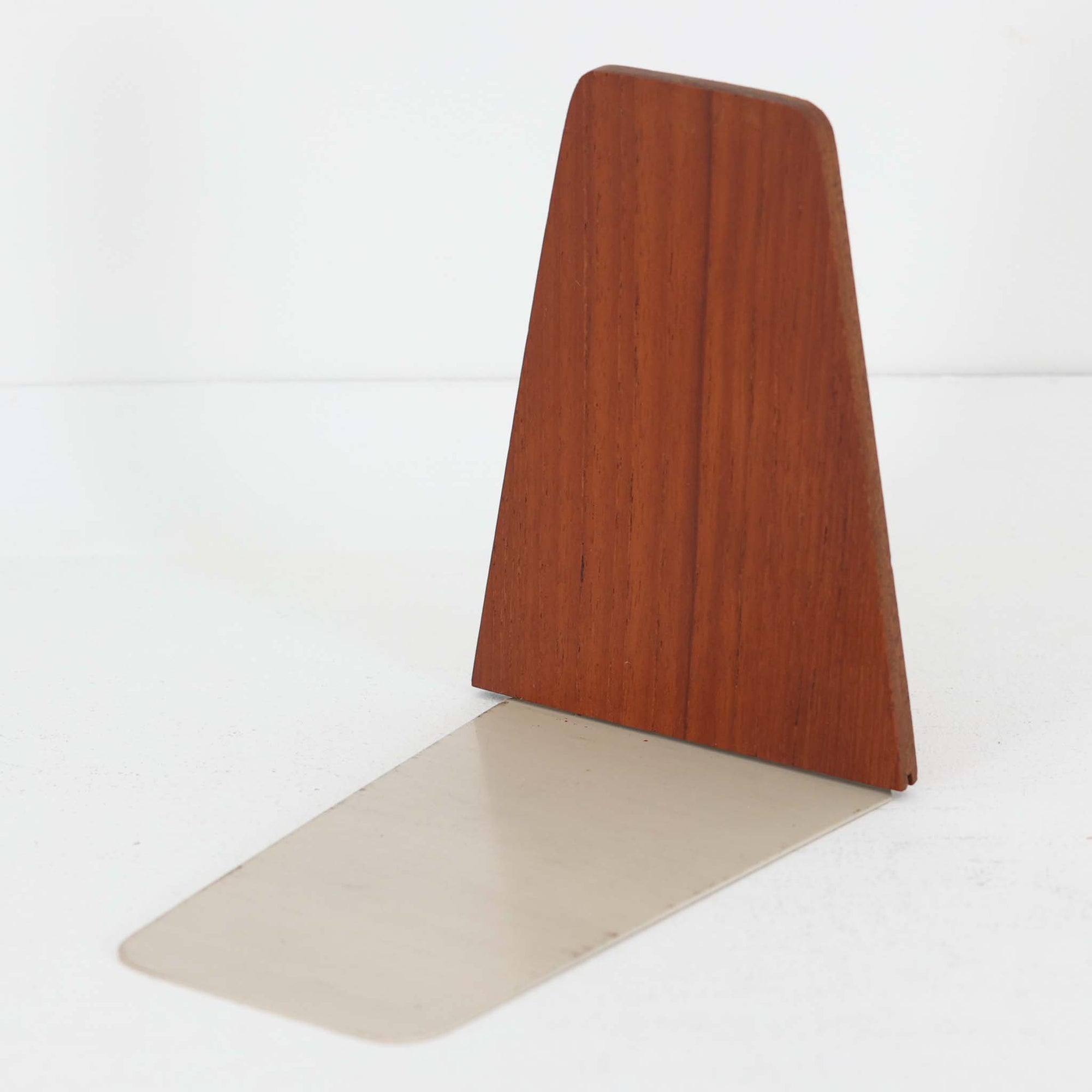 北欧デザインの温もりを感じさせる、デンマーク製ヴィンテージのブックエンドです。1960〜80年代頃に製造されたとみられ、素材には希少なチーク材を使用。深みのある色合いと美しい木目は、経年によってさらに味わいを増し、空間に落ち着きと上質さをもたらします。シンプルでありながら洗練されたフォルムは、北欧モダンらしいミニマルな美しさを体現しており、実用性とインテリア性を兼ね備え、書棚やデスクまわりを上品に演出します。