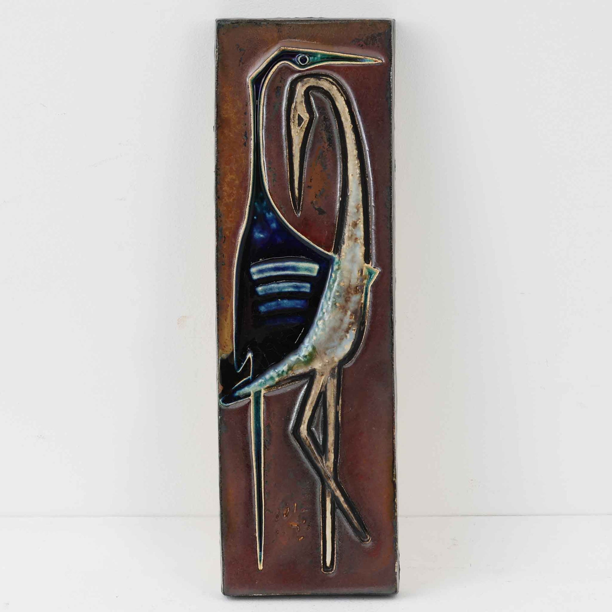 この作品は、ドイツの芸術家 Helmut Friedrich Schaffenacker による、1960年代〜1970年代のミッドセンチュリー陶器アート。幾何学的かつオーガニックな動物モチーフ（おそらく「トラン＝鶴／鶴の群れ」を描いたとされるレリーフ）が、力強く、かつ緻密に立体表現された壁掛けプレートです。モダンでもありどこか温かみのある表情は、1950〜70年代のヨーロッパ陶芸の実験精神を現代に伝える、たいへん貴重な一枚です。