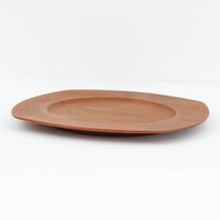 1960年代、デンマーク・モダンの黄金期にポール・クヌーセンが手がけたチーク無垢材のプレートです。「実用工芸」を意味するブランド名の通り、木の質感を活かした滑らかな曲線と、洗練されたミニマルな造形美が魅力。半世紀を経て深く色づいたチーク材は「木の宝石」と称されるほど美しく、食卓に温かな品格を添えます。食器としてはもちろん、インテリアトレイとしても重宝する、一期一会のヴィンテージ名作です。