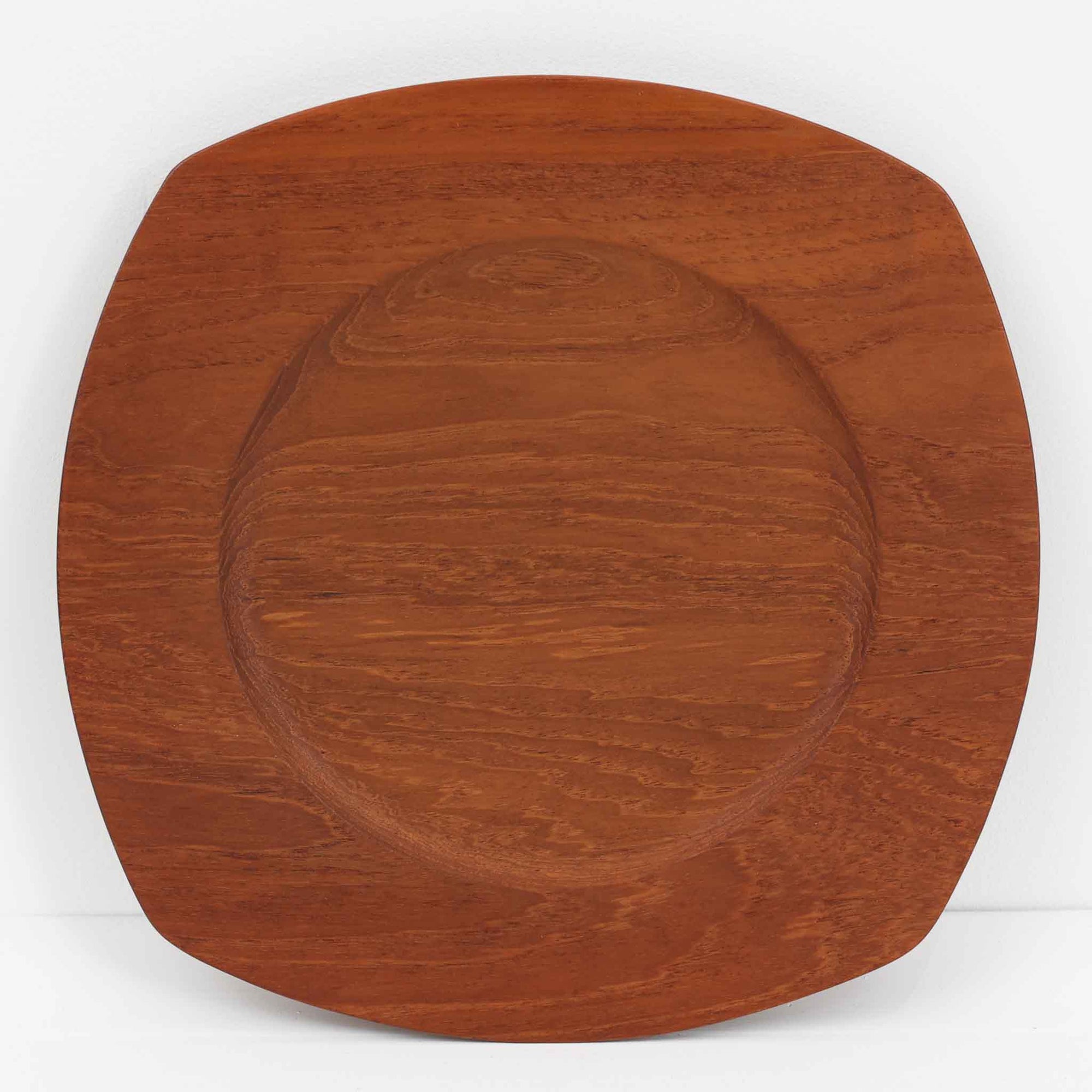 1960年代、デンマーク・モダンの黄金期にポール・クヌーセンが手がけたチーク無垢材のプレートです。「実用工芸」を意味するブランド名の通り、木の質感を活かした滑らかな曲線と、洗練されたミニマルな造形美が魅力。半世紀を経て深く色づいたチーク材は「木の宝石」と称されるほど美しく、食卓に温かな品格を添えます。食器としてはもちろん、インテリアトレイとしても重宝する、一期一会のヴィンテージ名作です。