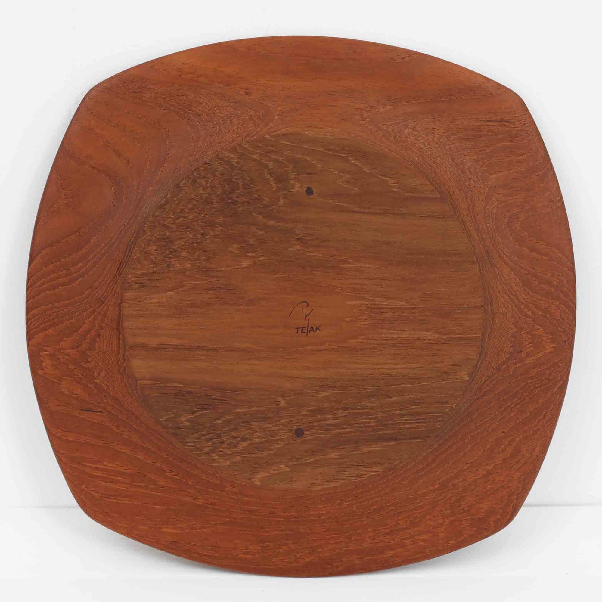 1960年代、デンマーク・モダンの黄金期にポール・クヌーセンが手がけたチーク無垢材のプレートです。「実用工芸」を意味するブランド名の通り、木の質感を活かした滑らかな曲線と、洗練されたミニマルな造形美が魅力。半世紀を経て深く色づいたチーク材は「木の宝石」と称されるほど美しく、食卓に温かな品格を添えます。食器としてはもちろん、インテリアトレイとしても重宝する、一期一会のヴィンテージ名作です。