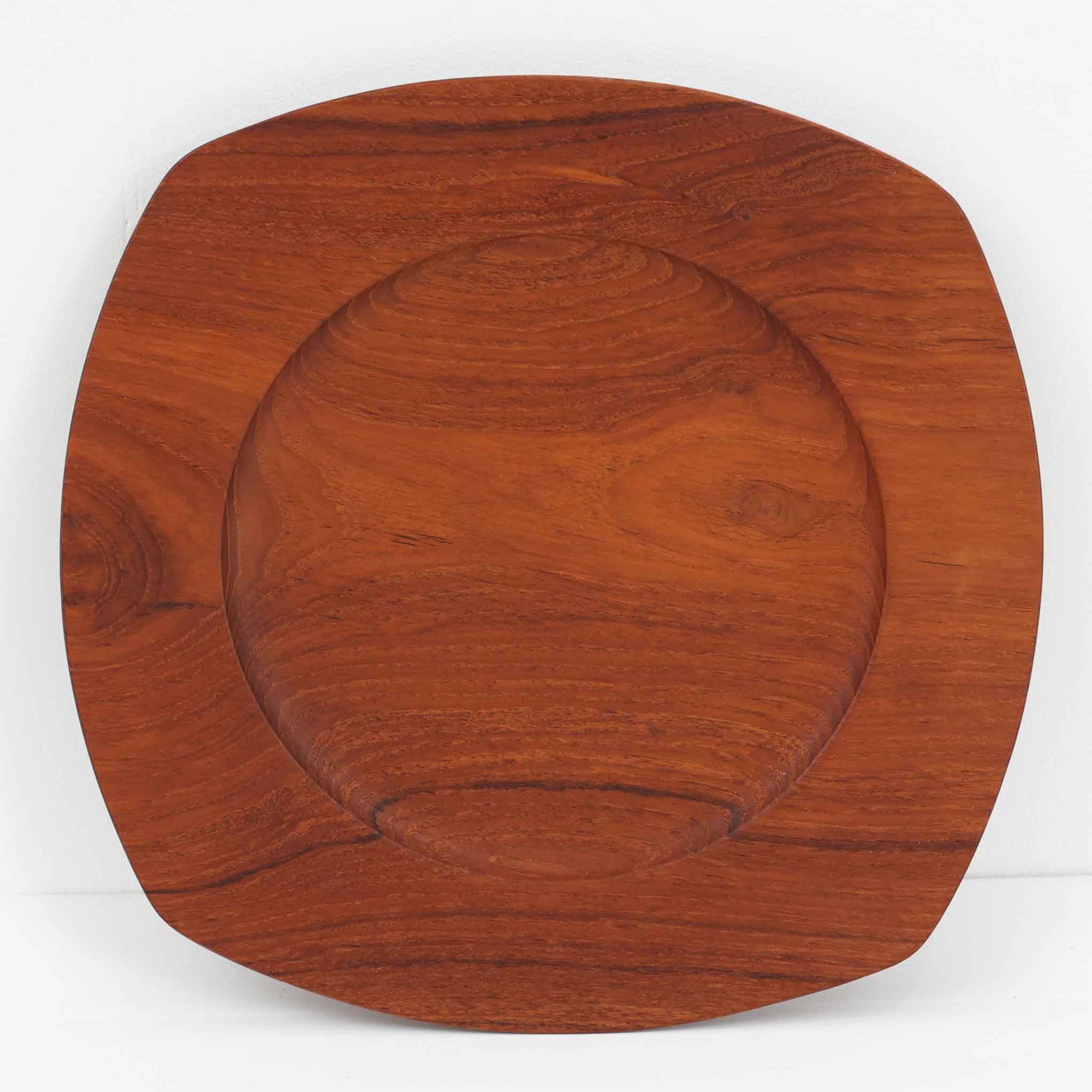 1960年代、デンマーク・モダンの黄金期にポール・クヌーセンが手がけたチーク無垢材のプレートです。「実用工芸」を意味するブランド名の通り、木の質感を活かした滑らかな曲線と、洗練されたミニマルな造形美が魅力。半世紀を経て深く色づいたチーク材は「木の宝石」と称されるほど美しく、食卓に温かな品格を添えます。食器としてはもちろん、インテリアトレイとしても重宝する、一期一会のヴィンテージ名作です。