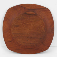 1960年代、デンマーク・モダンの黄金期にポール・クヌーセンが手がけたチーク無垢材のプレートです。「実用工芸」を意味するブランド名の通り、木の質感を活かした滑らかな曲線と、洗練されたミニマルな造形美が魅力。半世紀を経て深く色づいたチーク材は「木の宝石」と称されるほど美しく、食卓に温かな品格を添えます。食器としてはもちろん、インテリアトレイとしても重宝する、一期一会のヴィンテージ名作です。