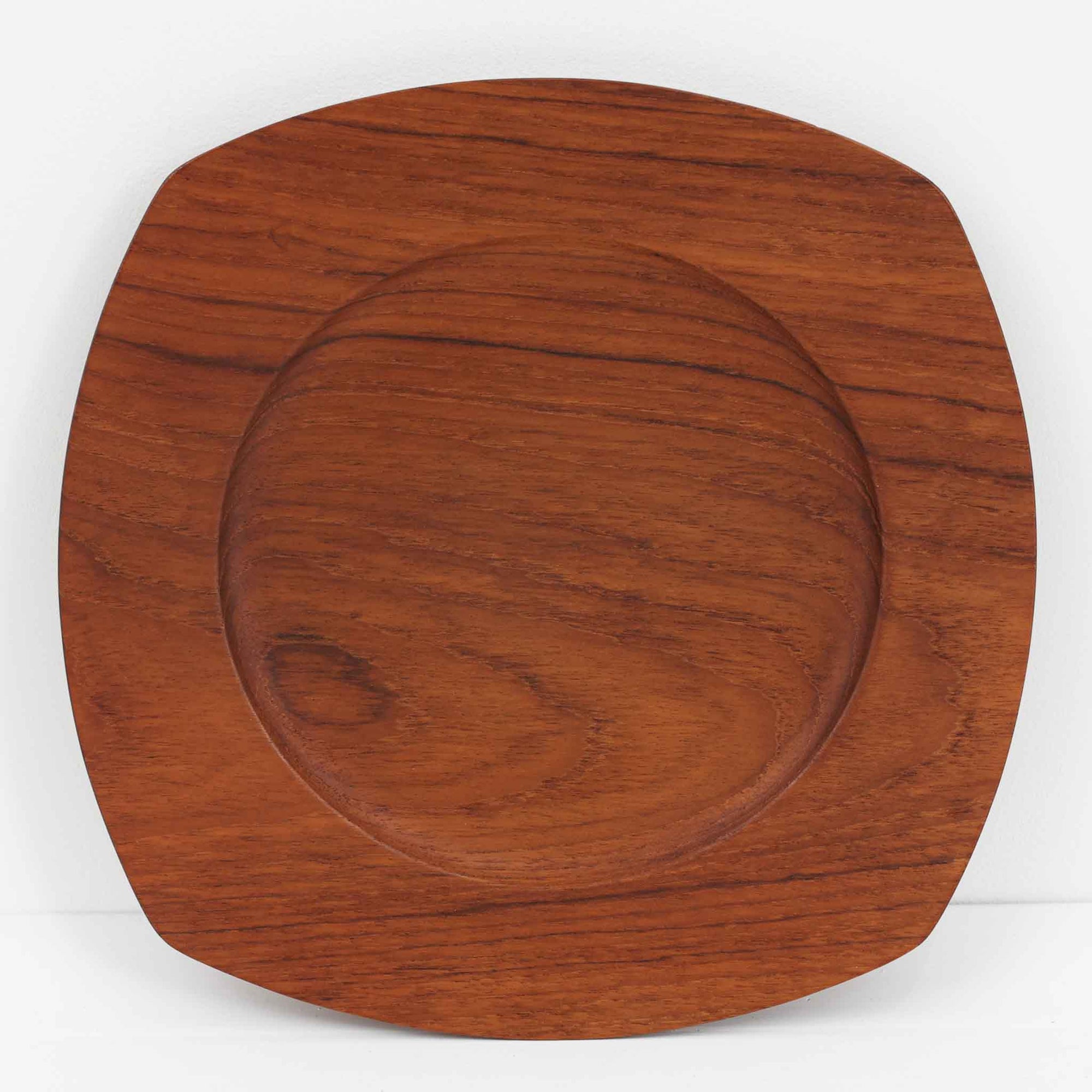 1960年代、デンマーク・モダンの黄金期にポール・クヌーセンが手がけたチーク無垢材のプレートです。「実用工芸」を意味するブランド名の通り、木の質感を活かした滑らかな曲線と、洗練されたミニマルな造形美が魅力。半世紀を経て深く色づいたチーク材は「木の宝石」と称されるほど美しく、食卓に温かな品格を添えます。食器としてはもちろん、インテリアトレイとしても重宝する、一期一会のヴィンテージ名作です。
