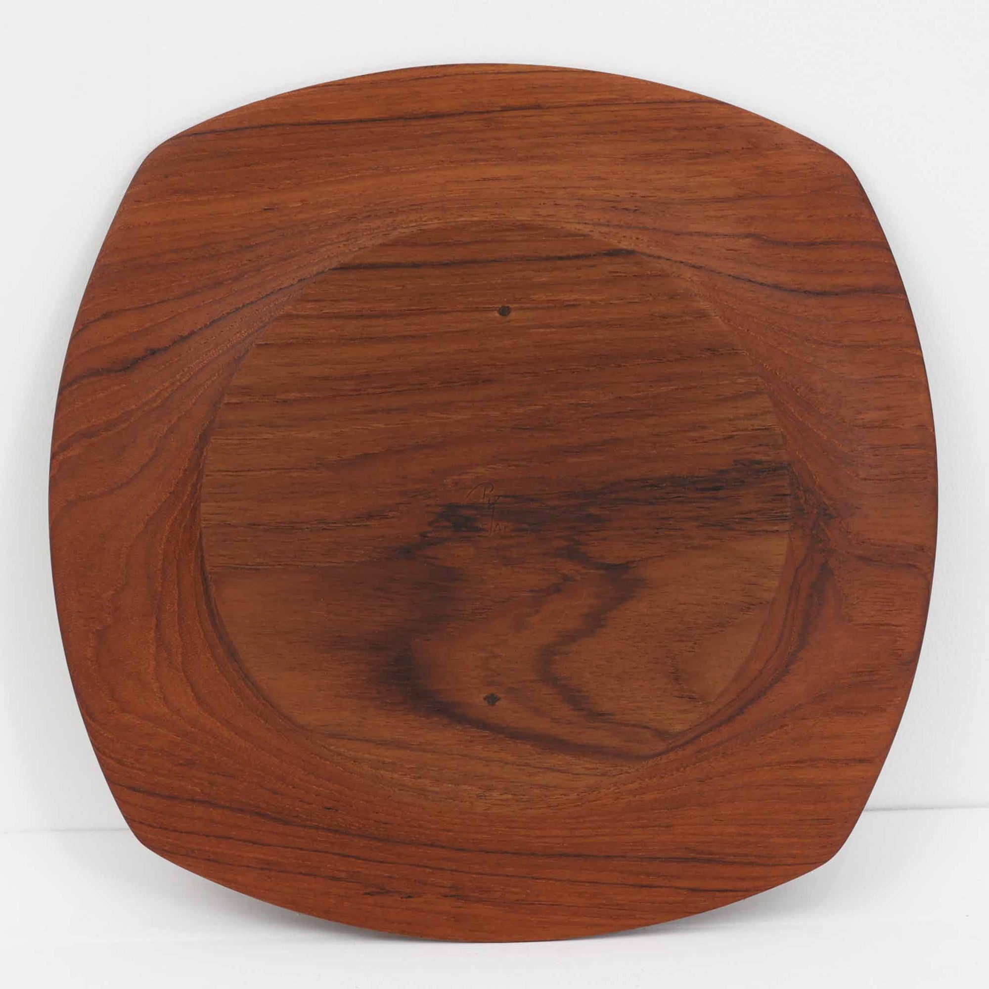 1960年代、デンマーク・モダンの黄金期にポール・クヌーセンが手がけたチーク無垢材のプレートです。「実用工芸」を意味するブランド名の通り、木の質感を活かした滑らかな曲線と、洗練されたミニマルな造形美が魅力。半世紀を経て深く色づいたチーク材は「木の宝石」と称されるほど美しく、食卓に温かな品格を添えます。食器としてはもちろん、インテリアトレイとしても重宝する、一期一会のヴィンテージ名作です。