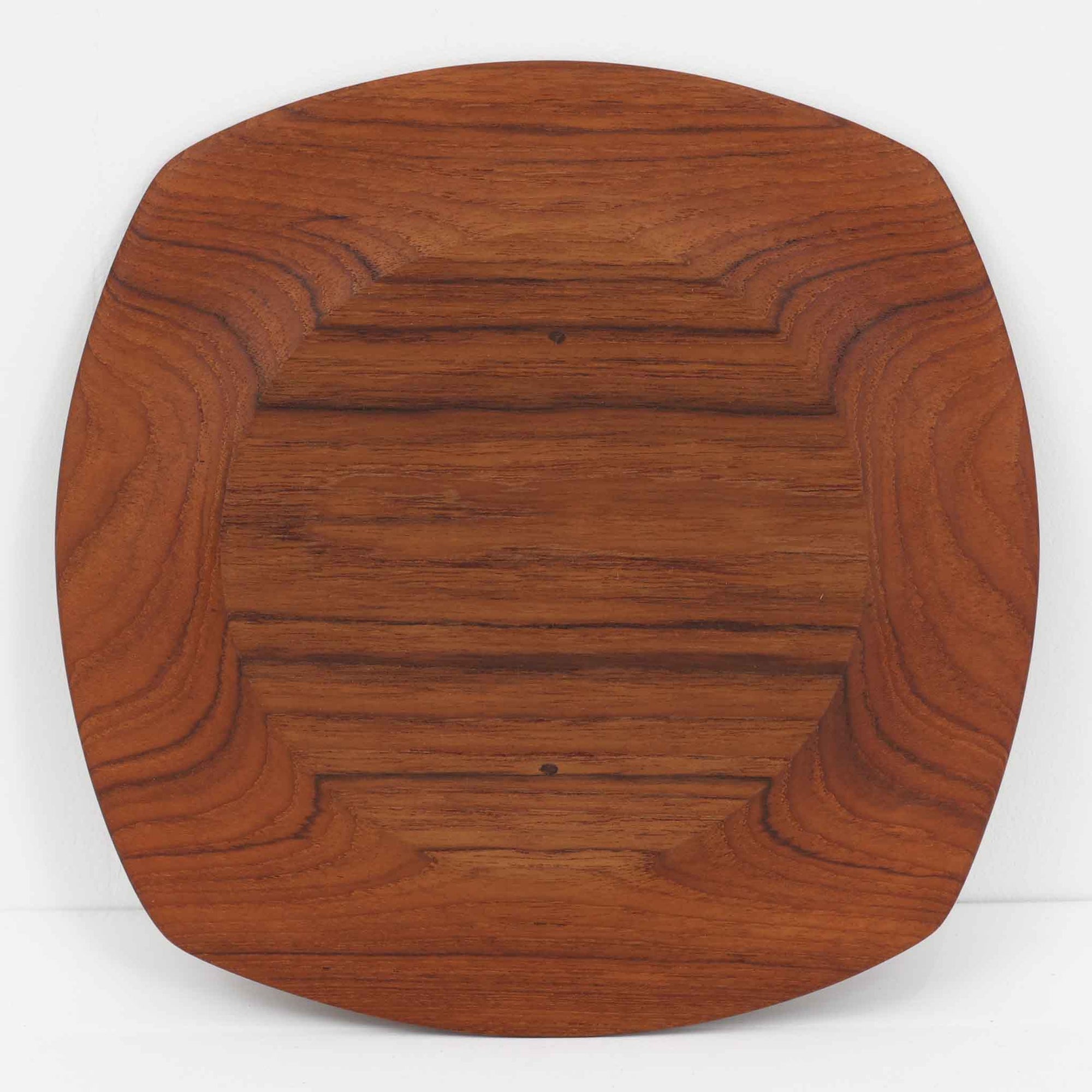 1960年代、デンマーク・モダンの黄金期にポール・クヌーセンが手がけたチーク無垢材のプレートです。「実用工芸」を意味するブランド名の通り、木の質感を活かした滑らかな曲線と、洗練されたミニマルな造形美が魅力。半世紀を経て深く色づいたチーク材は「木の宝石」と称されるほど美しく、食卓に温かな品格を添えます。食器としてはもちろん、インテリアトレイとしても重宝する、一期一会のヴィンテージ名作です。