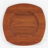 1960年代、デンマーク・モダンの黄金期にポール・クヌーセンが手がけたチーク無垢材のプレートです。「実用工芸」を意味するブランド名の通り、木の質感を活かした滑らかな曲線と、洗練されたミニマルな造形美が魅力。半世紀を経て深く色づいたチーク材は「木の宝石」と称されるほど美しく、食卓に温かな品格を添えます。食器としてはもちろん、インテリアトレイとしても重宝する、一期一会のヴィンテージ名作です。