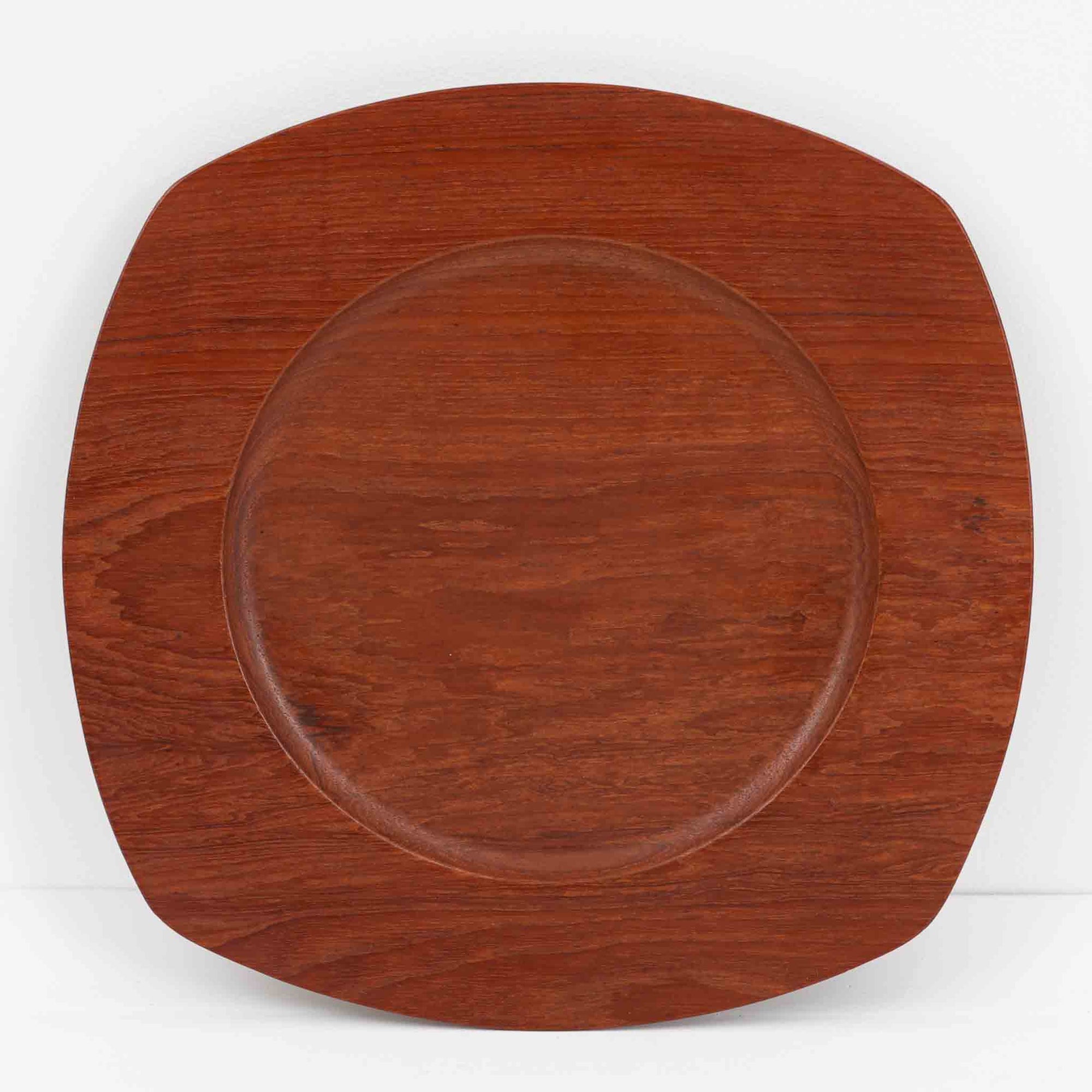 1960年代、デンマーク・モダンの黄金期にポール・クヌーセンが手がけたチーク無垢材のプレートです。「実用工芸」を意味するブランド名の通り、木の質感を活かした滑らかな曲線と、洗練されたミニマルな造形美が魅力。半世紀を経て深く色づいたチーク材は「木の宝石」と称されるほど美しく、食卓に温かな品格を添えます。食器としてはもちろん、インテリアトレイとしても重宝する、一期一会のヴィンテージ名作です。