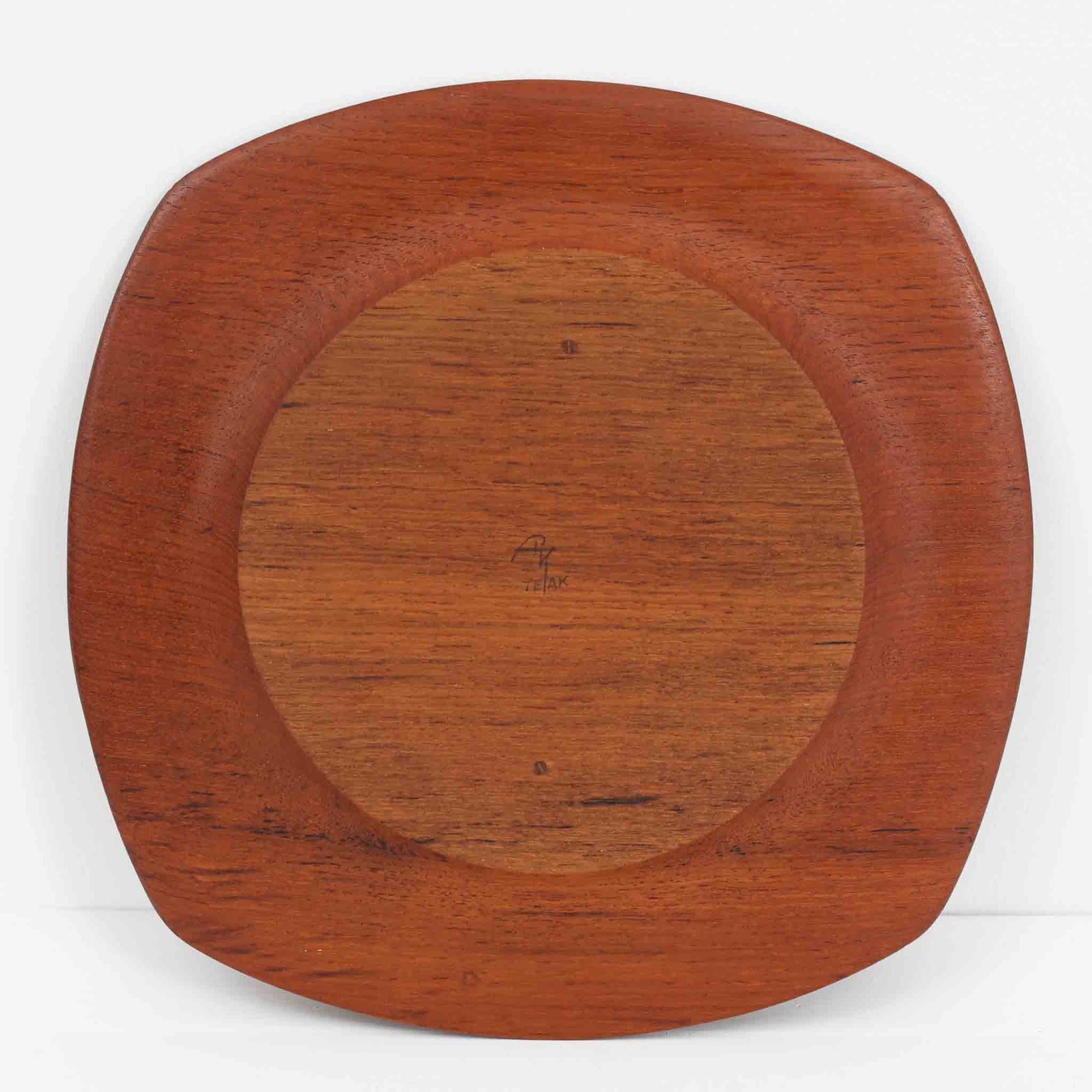 1960年代、デンマーク・モダンの黄金期にポール・クヌーセンが手がけたチーク無垢材のプレートです。「実用工芸」を意味するブランド名の通り、木の質感を活かした滑らかな曲線と、洗練されたミニマルな造形美が魅力。半世紀を経て深く色づいたチーク材は「木の宝石」と称されるほど美しく、食卓に温かな品格を添えます。食器としてはもちろん、インテリアトレイとしても重宝する、一期一会のヴィンテージ名作です。