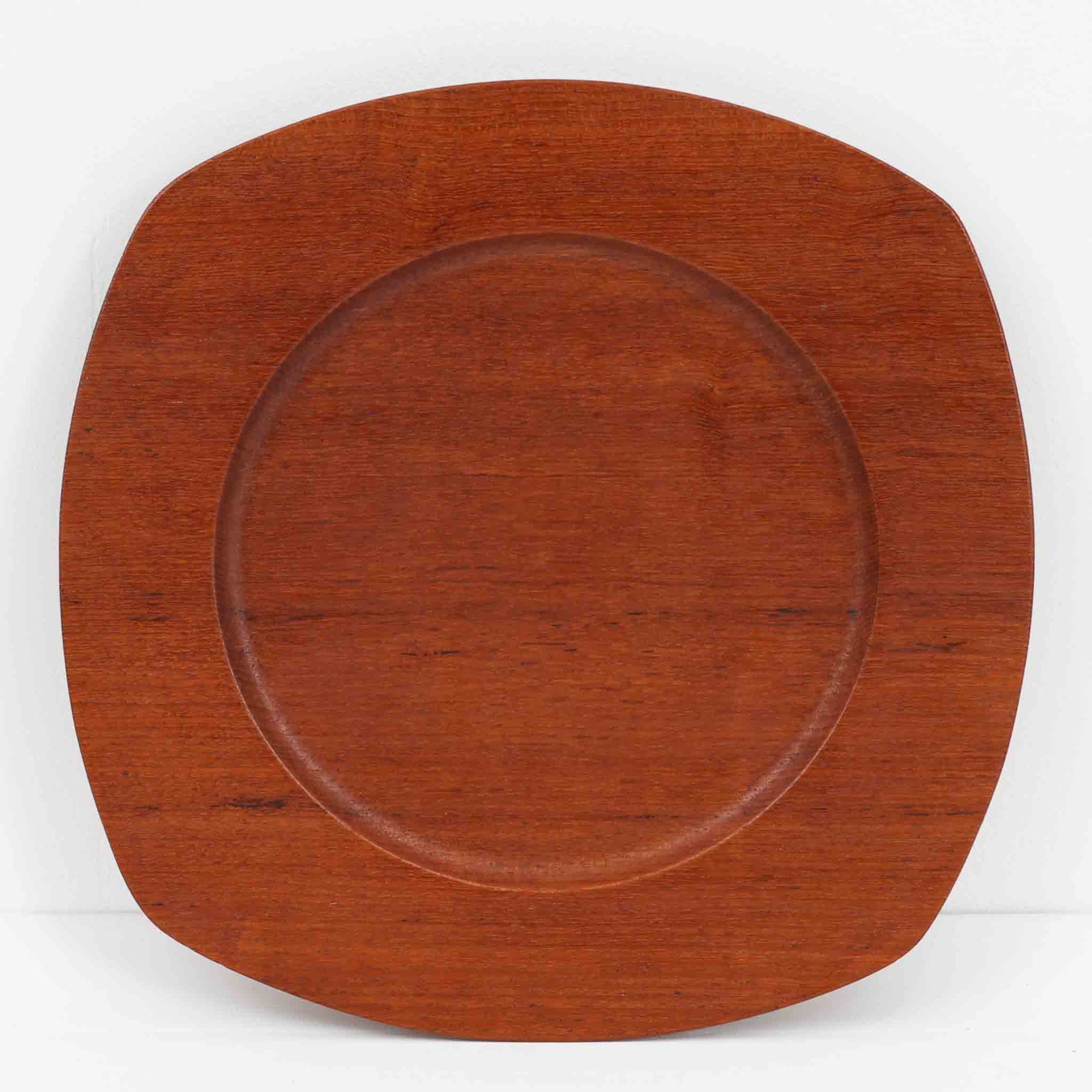 1960年代、デンマーク・モダンの黄金期にポール・クヌーセンが手がけたチーク無垢材のプレートです。「実用工芸」を意味するブランド名の通り、木の質感を活かした滑らかな曲線と、洗練されたミニマルな造形美が魅力。半世紀を経て深く色づいたチーク材は「木の宝石」と称されるほど美しく、食卓に温かな品格を添えます。食器としてはもちろん、インテリアトレイとしても重宝する、一期一会のヴィンテージ名作です。