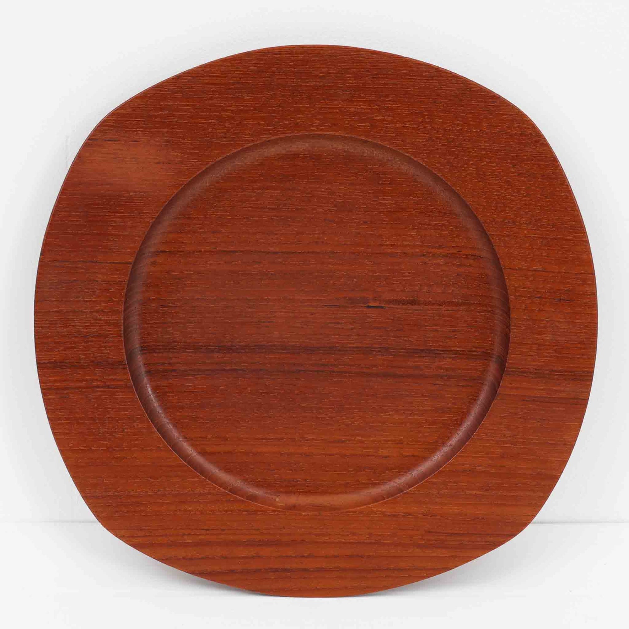 1960年代、デンマーク・モダンの黄金期にポール・クヌーセンが手がけたチーク無垢材のプレートです。「実用工芸」を意味するブランド名の通り、木の質感を活かした滑らかな曲線と、洗練されたミニマルな造形美が魅力。半世紀を経て深く色づいたチーク材は「木の宝石」と称されるほど美しく、食卓に温かな品格を添えます。食器としてはもちろん、インテリアトレイとしても重宝する、一期一会のヴィンテージ名作です。