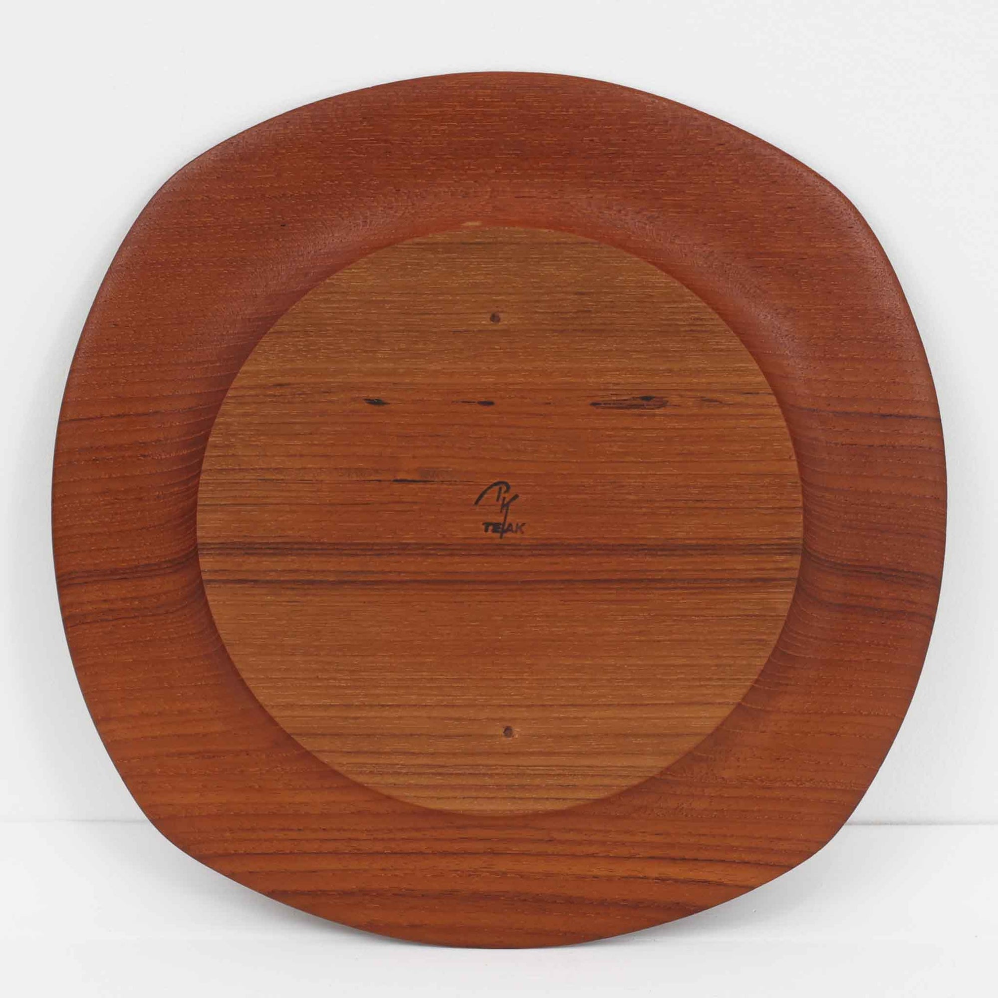 1960年代、デンマーク・モダンの黄金期にポール・クヌーセンが手がけたチーク無垢材のプレートです。「実用工芸」を意味するブランド名の通り、木の質感を活かした滑らかな曲線と、洗練されたミニマルな造形美が魅力。半世紀を経て深く色づいたチーク材は「木の宝石」と称されるほど美しく、食卓に温かな品格を添えます。食器としてはもちろん、インテリアトレイとしても重宝する、一期一会のヴィンテージ名作です。