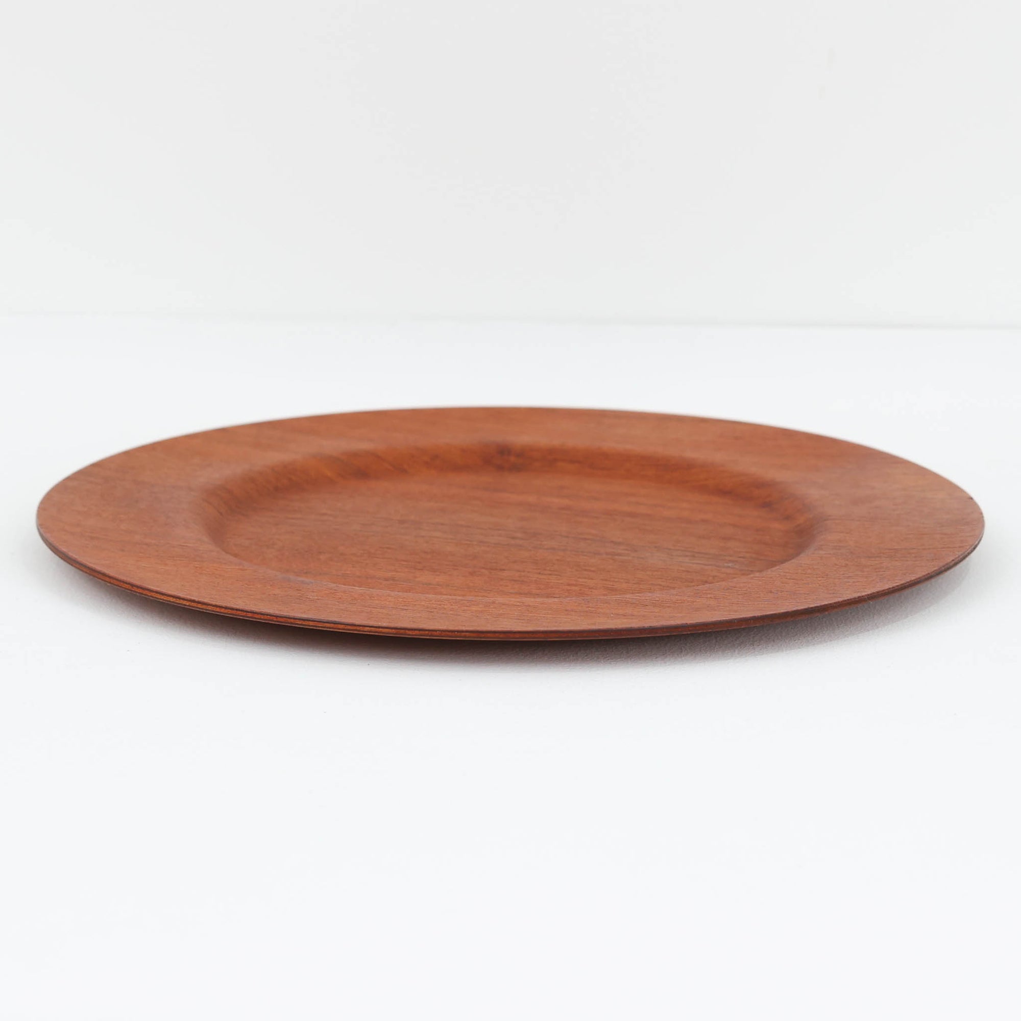 北欧ヴィンテージらしい、あたたかみのある木目が魅力のチーク材プレートです。突板（プライウッド）仕様のため、軽やかで扱いやすく、テーブルの雰囲気を上品にまとめてくれます。メーカー刻印等は見当たらず詳細は不明ですが、形状や素材感から1960年代頃のデンマーク製と思われます。アクセサリートレイや小物置きとしても使いやすい一枚です。