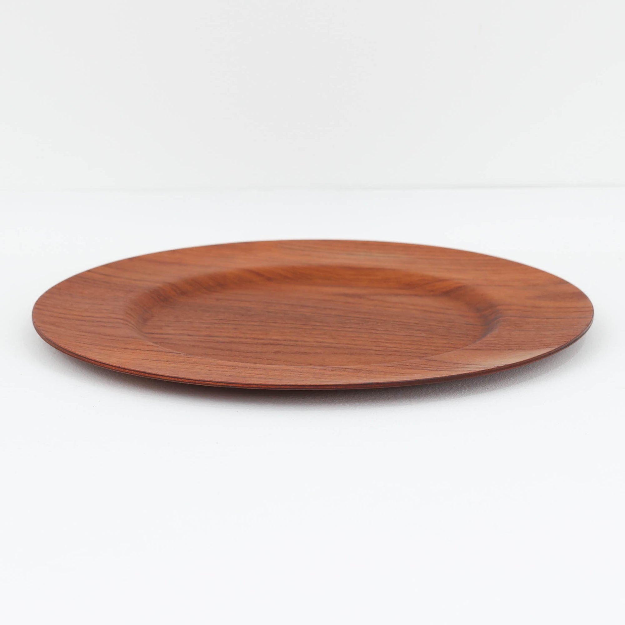 北欧ヴィンテージらしい、あたたかみのある木目が魅力のチーク材プレートです。突板（プライウッド）仕様のため、軽やかで扱いやすく、テーブルの雰囲気を上品にまとめてくれます。メーカー刻印等は見当たらず詳細は不明ですが、形状や素材感から1960年代頃のデンマーク製と思われます。アクセサリートレイや小物置きとしても使いやすい一枚です。