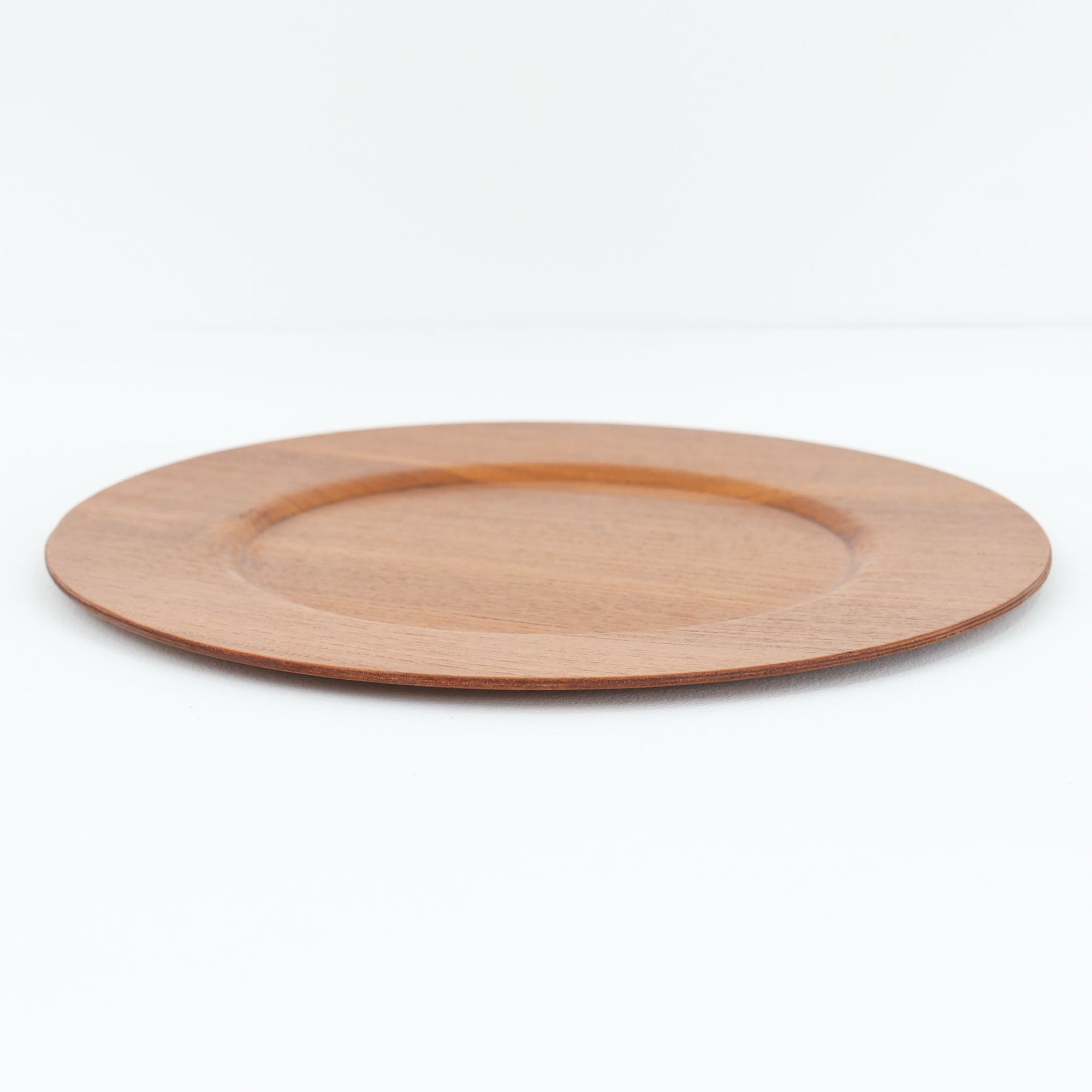 北欧ヴィンテージらしい、あたたかみのある木目が魅力のチーク材プレートです。突板（プライウッド）仕様のため、軽やかで扱いやすく、テーブルの雰囲気を上品にまとめてくれます。メーカー刻印等は見当たらず詳細は不明ですが、形状や素材感から1960年代頃のデンマーク製と思われます。アクセサリートレイや小物置きとしても使いやすい一枚です。