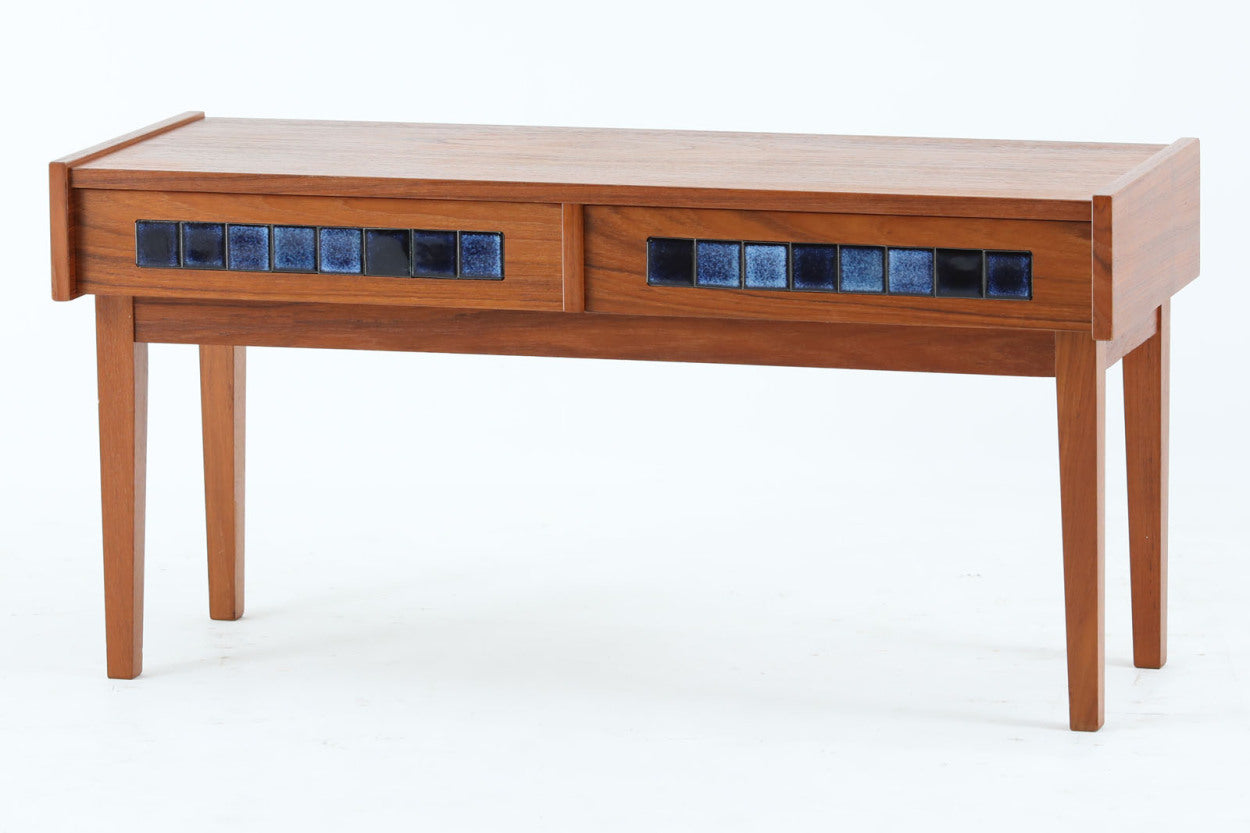 こちらは、北欧より買い付けたワイドチェストです。優れた品質のチーク材を本体に使用し、引き出し前板には鮮やかなブルーのタイルが施されており、デザインのアクセントとなっています。また、左右に取り付けられた細身のテーパー脚が、全体に洗練された印象を与えています。幅90cmのワイドサイズなので、ローボードやセンターテーブルとしてもお使いいただけます。