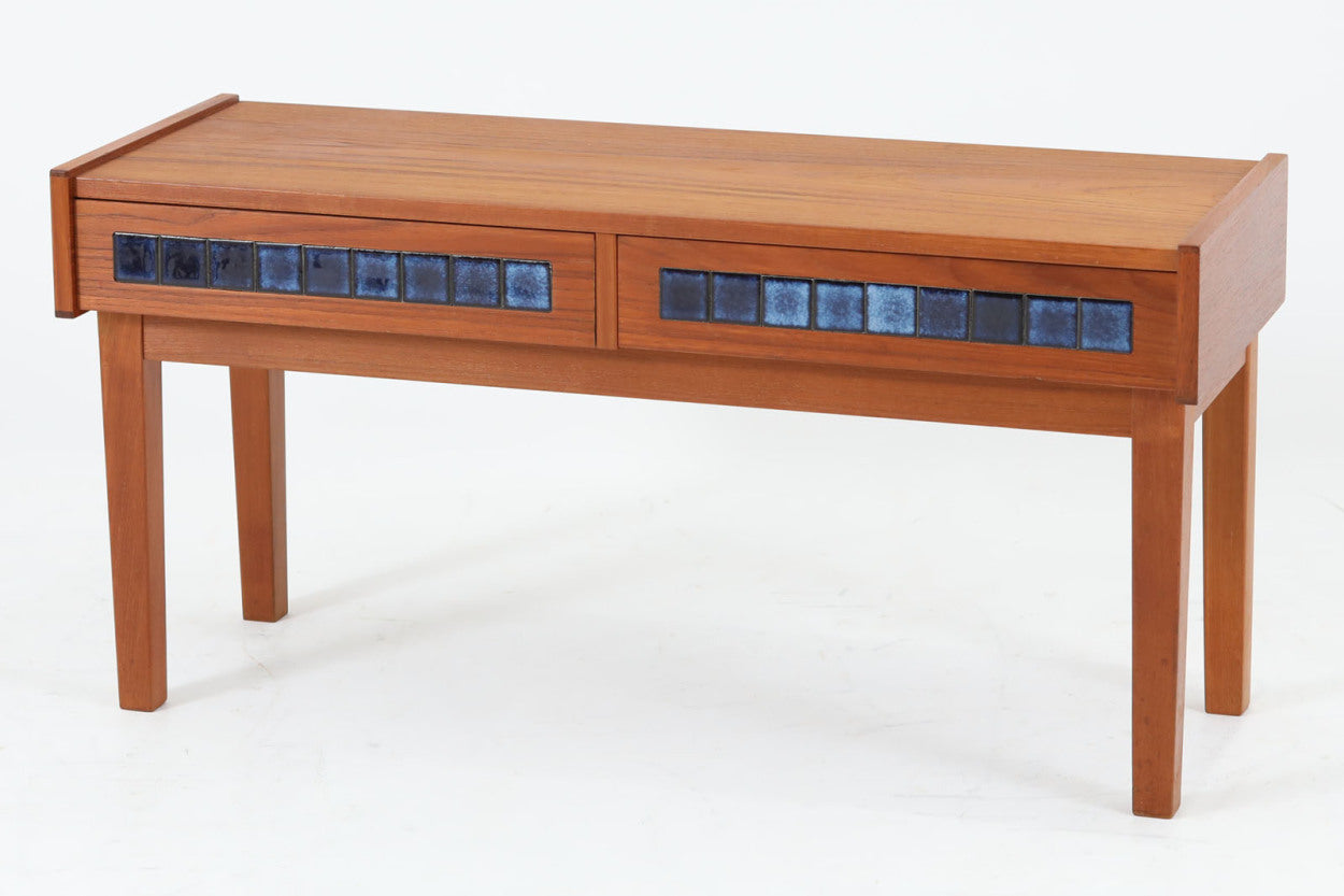 こちらは、北欧より買い付けたワイドチェストです。優れた品質のチーク材を本体に使用し、引き出し前板には鮮やかなブルーのタイルが施されており、デザインのアクセントとなっています。また、左右に取り付けられた細身のテーパー脚が、全体に洗練された印象を与えています。幅90cmのワイドサイズなので、ローボードやセンターテーブルとしてもお使いいただけます。