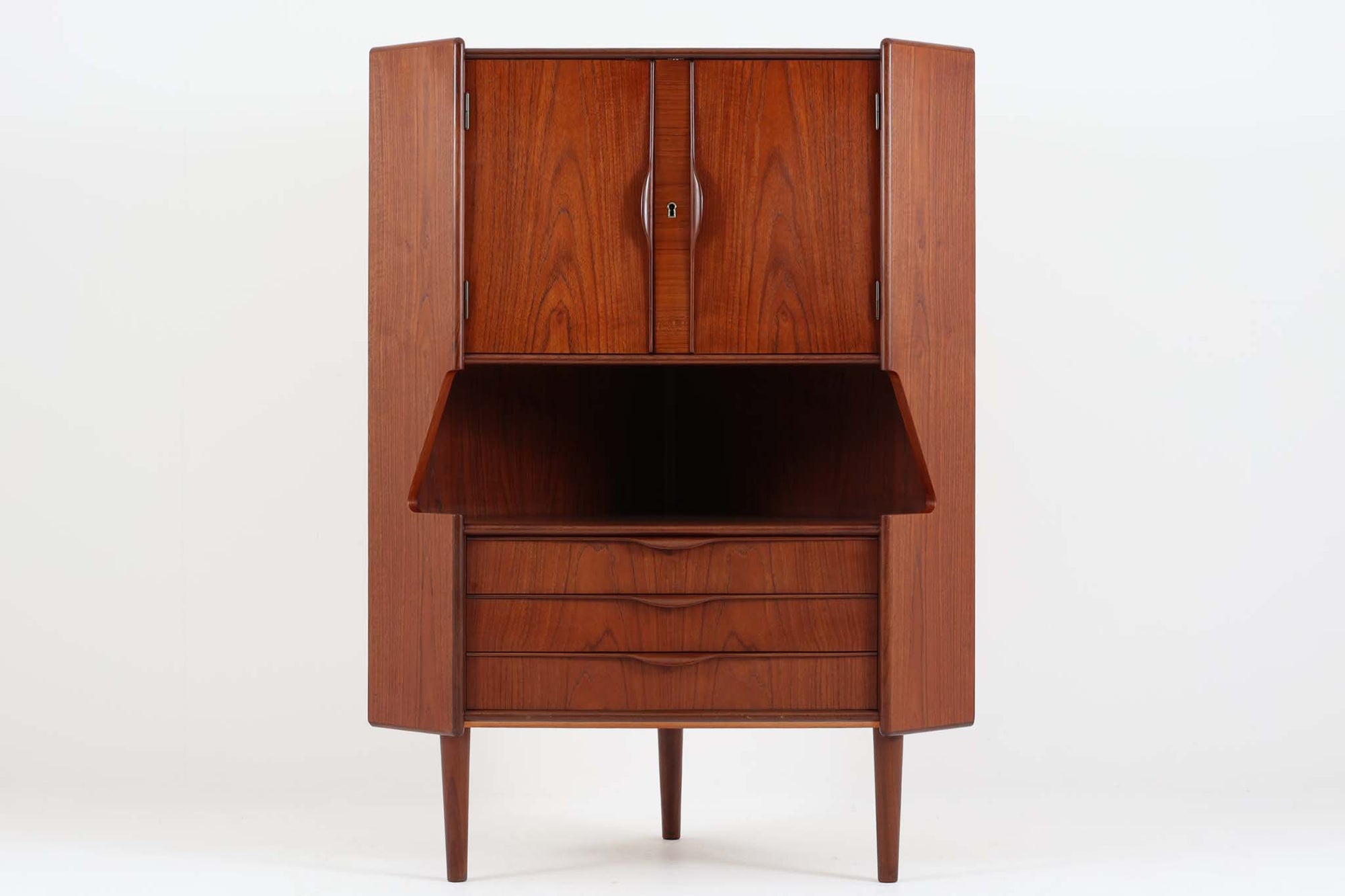 北欧より買い付けたコーナーキャビネットです。上質なチーク材で作られ、デンマークらしい取手がアクセントを添えます。下段は引き出し、中央はオープンスペース、そして上段は扉収納と、使い勝手も考え抜かれたデザインです。内部の背面にはガラスが施され、美しい収納品を一目で楽しむことができます。お部屋に北欧の温かみとクラシカルな雰囲気を添える、特別な一品です。