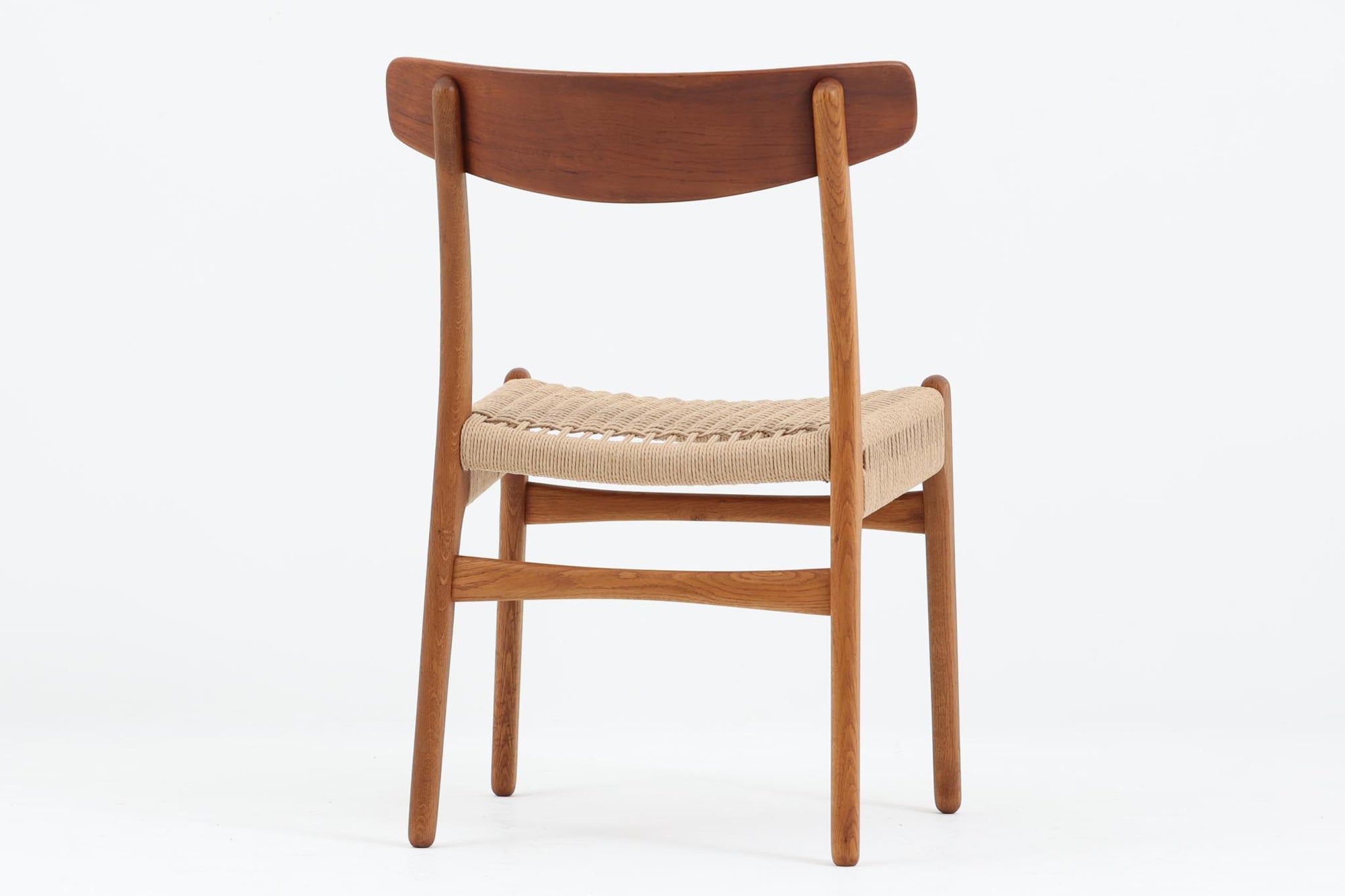 CH23は1950年、ウェグナーがCarl Hansen＆Son社のためにデザインした最初の椅子コレクションの1つです。繊細でありながらも力強いデザインが特徴で、手作りの職人技で作り上げられた無垢の木材が、チェアに優雅で自然な風合いをもたらします。特に背もたれと後ろ脚の繋ぎ目は、そのデザインの特徴となっており、独自性とクラフトマンシップの見本と言えるでしょう。CH23ダイニングチェアは、2017年にCarl Hansen＆Son社より復刻されましたが、チーク×オーク材のモデルはビンテージ品でのみ入手可能となっています。