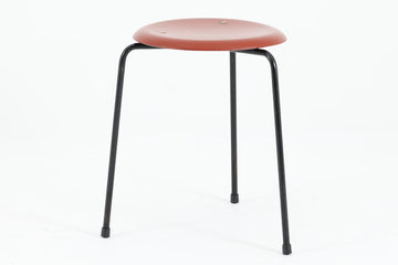 1954年、デンマークのデザイナー、Arne Jacobsen（アルネ・ヤコブセン）によって発表された3本脚のスツール、「DOT（ドット）」。このスツールは、ヤコブセンが手がけた「ルードブレ市庁舎」のロビーで待合席として使用されていました。1970年には4本脚のバージョンも登場しましたが、3本脚のモデルは同年に廃盤となり、現在はビンテージ品のみで入手可能です。オフィスや自宅での日常的な使用はもちろん、予備の椅子としても便利なこのスツールは、シンプルなデザインが魅力です。座面の中央がわずかにくぼんでおり、座った際にフィット感を生み出します。シンプルながらもヤコブセンのこだわりが感じられ、また、単なるスツールとしてだけでなく、ソファの横に置いて本や小物を置くサイドテーブルとしても活用できます。前オーナーによってリペイントされています。座面裏には薄っすらとFritz Hansen社の刻印がございます。