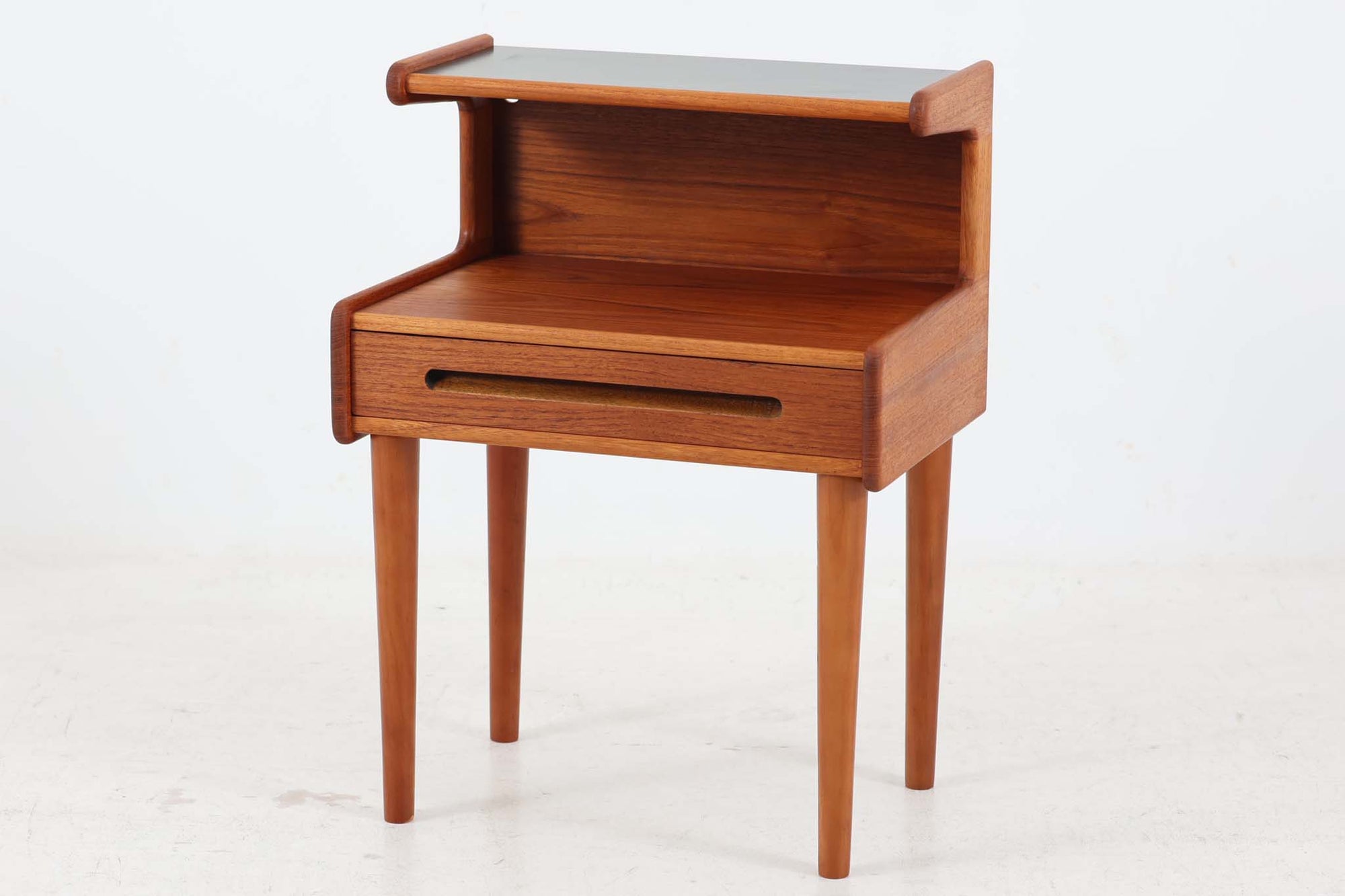 デンマークより買い付けた小さなサイドチェストです。背面には壁掛け用の穴が開いているため、脚を取り外してウォールシェルフとしてもご使用いただけます。本体側面にはチーク無垢材が使用されていたり、取手のデザインなどクオリティーの高い作品です。天板上部には水物を飾っても輪染みになり辛い様に黒いラミネートの様な素材が使用されています。