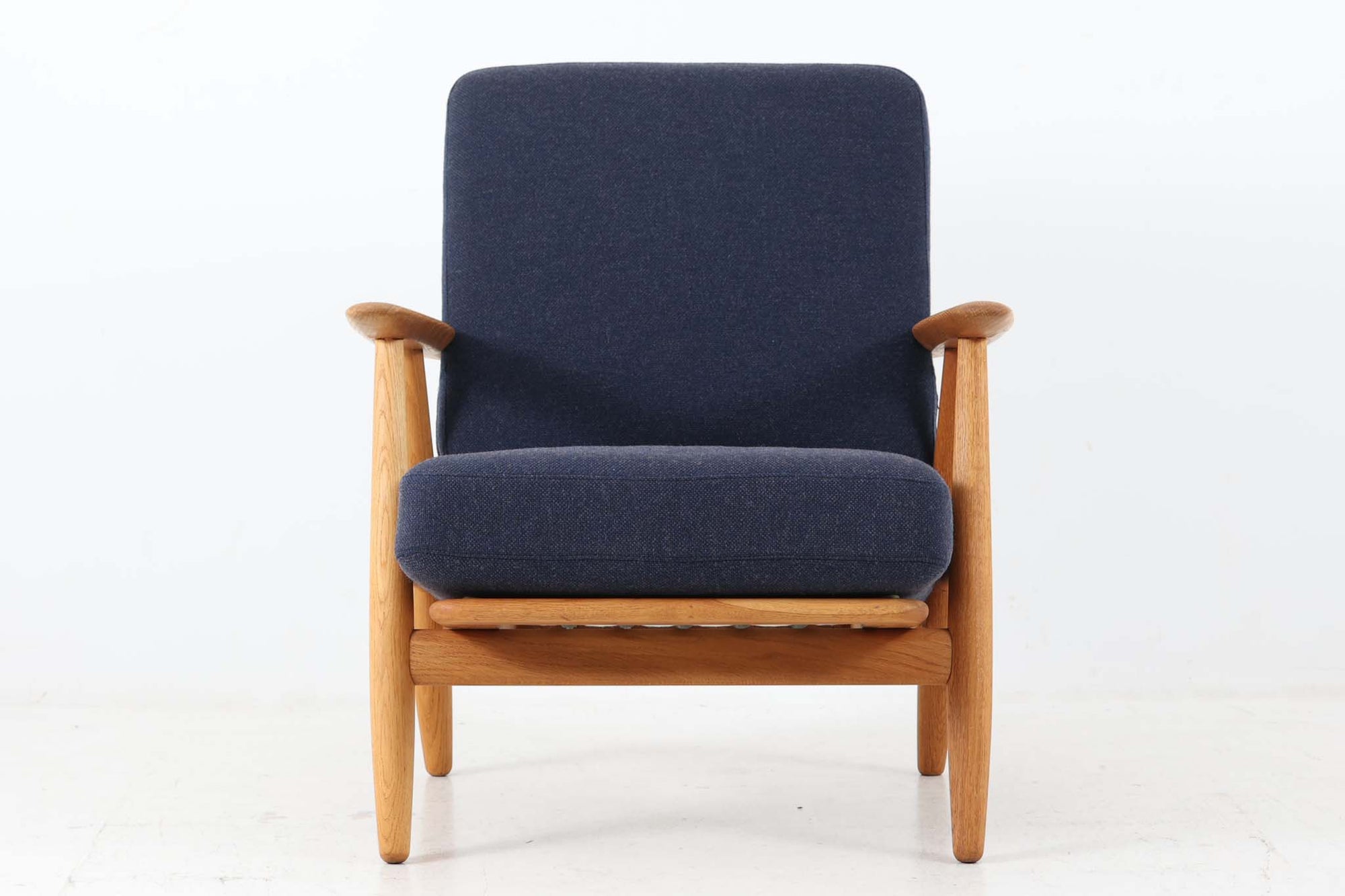 北欧家具を代表するソファ『GE240』です。現在ではビンテージ品のみ入手可能です。GE290のフレームより傾斜や曲線が多く使用されており、元々はベッド会社であるGETAmA社ならではのコイルスプリングが内包されたクッションの座り心地は、弾力があり心地良く、読書や映画などのリラックスタイムに最適です。立ち上がる際も適度なはね返りがあるので、動く時に億劫になる事はありません。HansJ.Wegnerならではの時代を超えた素晴らしいデザインです。横や背面から見るとまた違った表情を感じて頂けると思います。