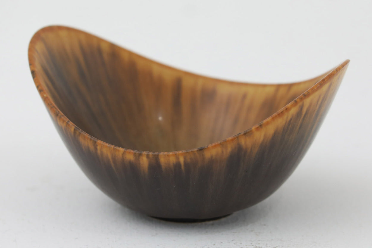 フィンランド人で彫刻家の父と、デンマーク人で陶芸家の母の元に育つGunnarNylundはデンマークで建築を学んだ後、Bing&amp;Grondahl窯、スウェーデンRorstrand窯に就業し、多くの作品を生み出しています。彼の作品は独特な流線型と釉薬が特徴で世界中で重宝されています。AROボウルは彼の最も代表的な作品で、その緩やかな美しいカーブが特徴です。また、さまざまな表情をみせる釉薬がコレクターにも人気がある理由です。