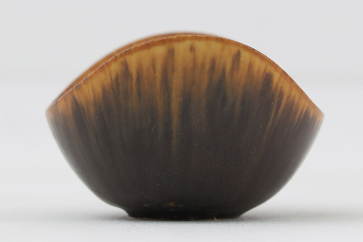 フィンランド人で彫刻家の父と、デンマーク人で陶芸家の母の元に育つGunnarNylundはデンマークで建築を学んだ後、Bing&amp;Grondahl窯、スウェーデンRorstrand窯に就業し、多くの作品を生み出しています。彼の作品は独特な流線型と釉薬が特徴で世界中で重宝されています。AROボウルは彼の最も代表的な作品で、その緩やかな美しいカーブが特徴です。また、さまざまな表情をみせる釉薬がコレクターにも人気がある理由です。